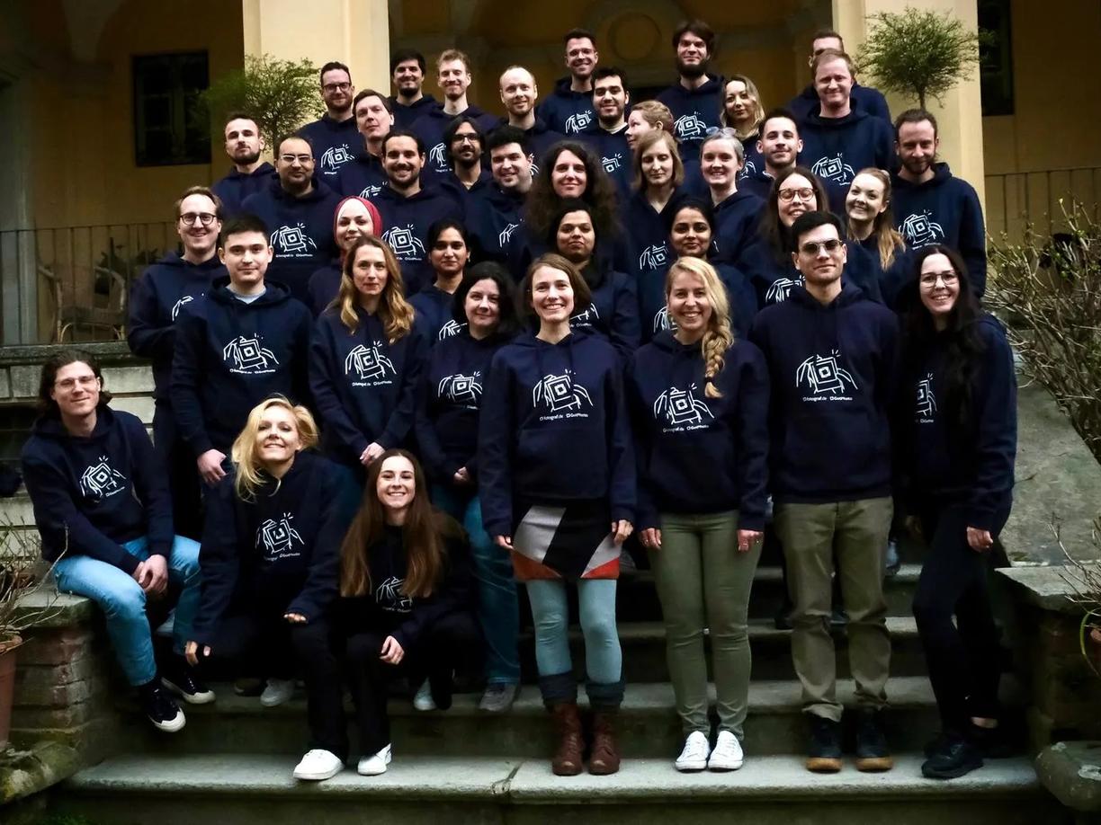 A group of people standing on steps, all wearing matching navy blue hoodies with a logo on the front.