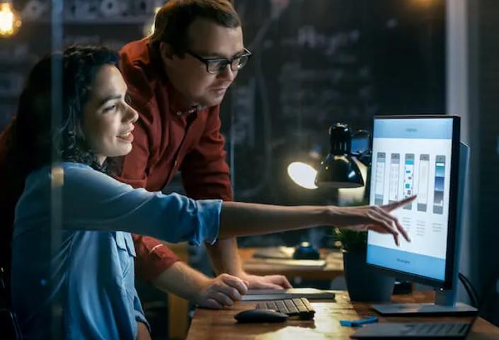 Photo of two people working by a computer