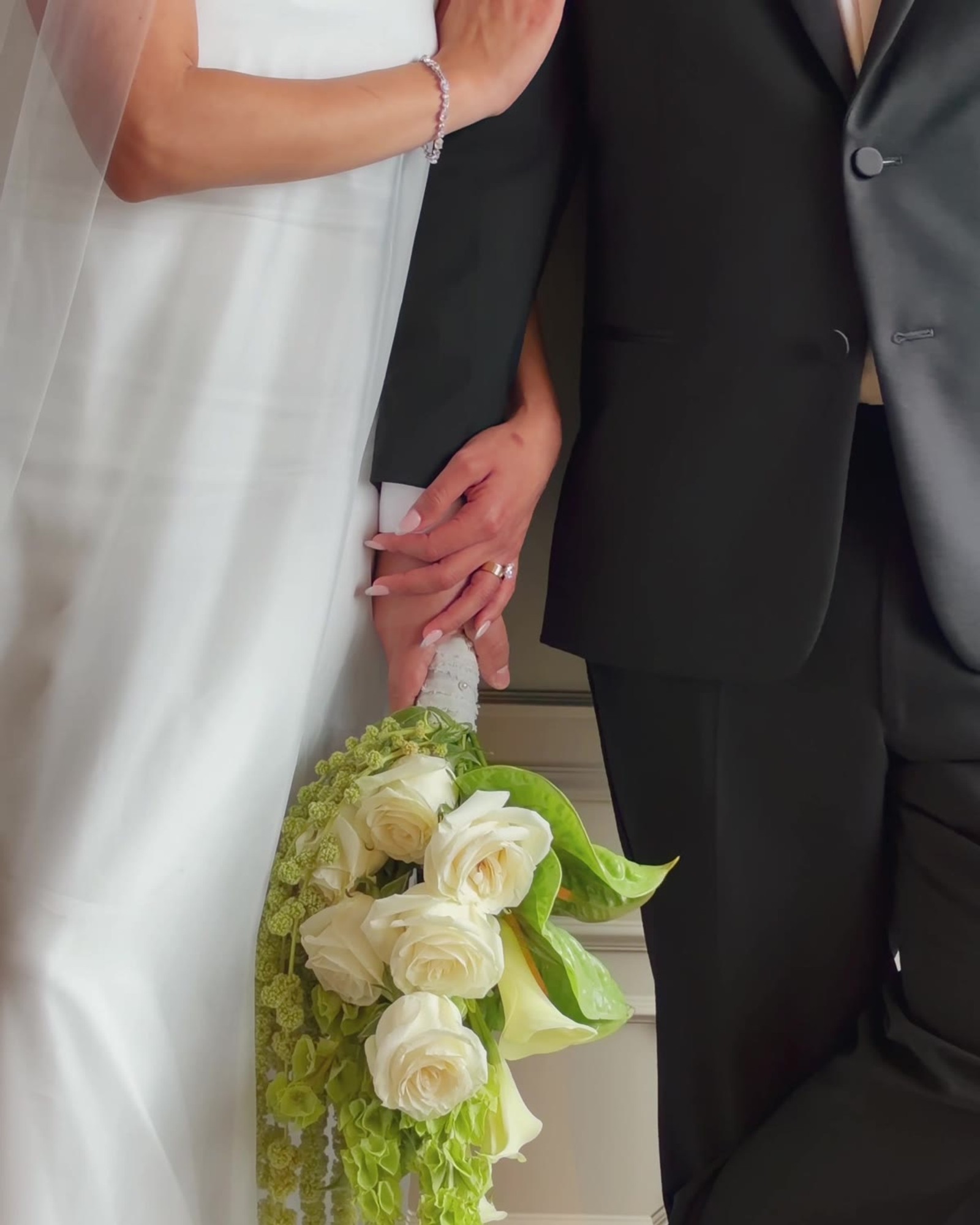 The couple's hands and a bouquet of white roses