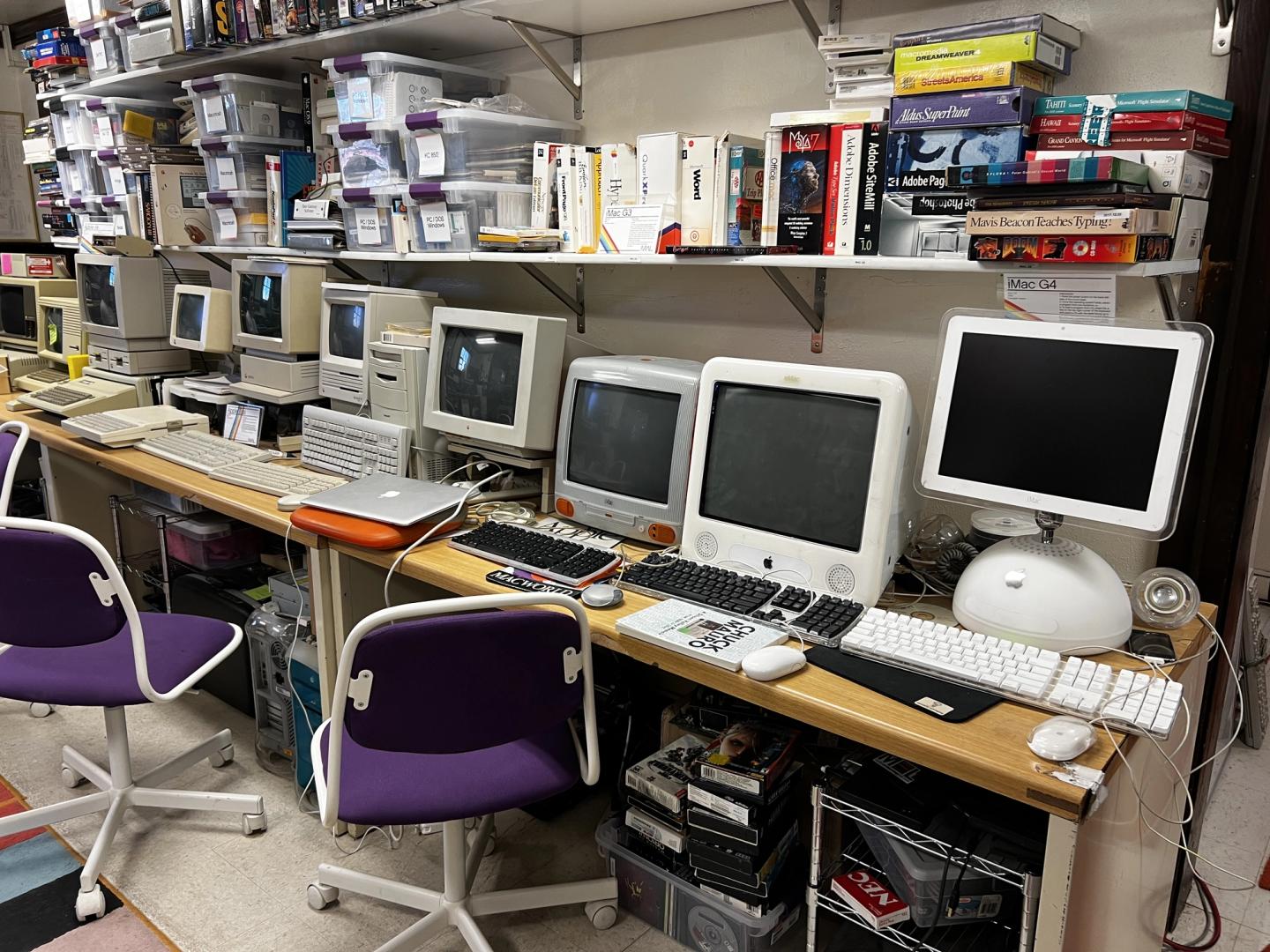 a line of old macintosh desktops with chairs