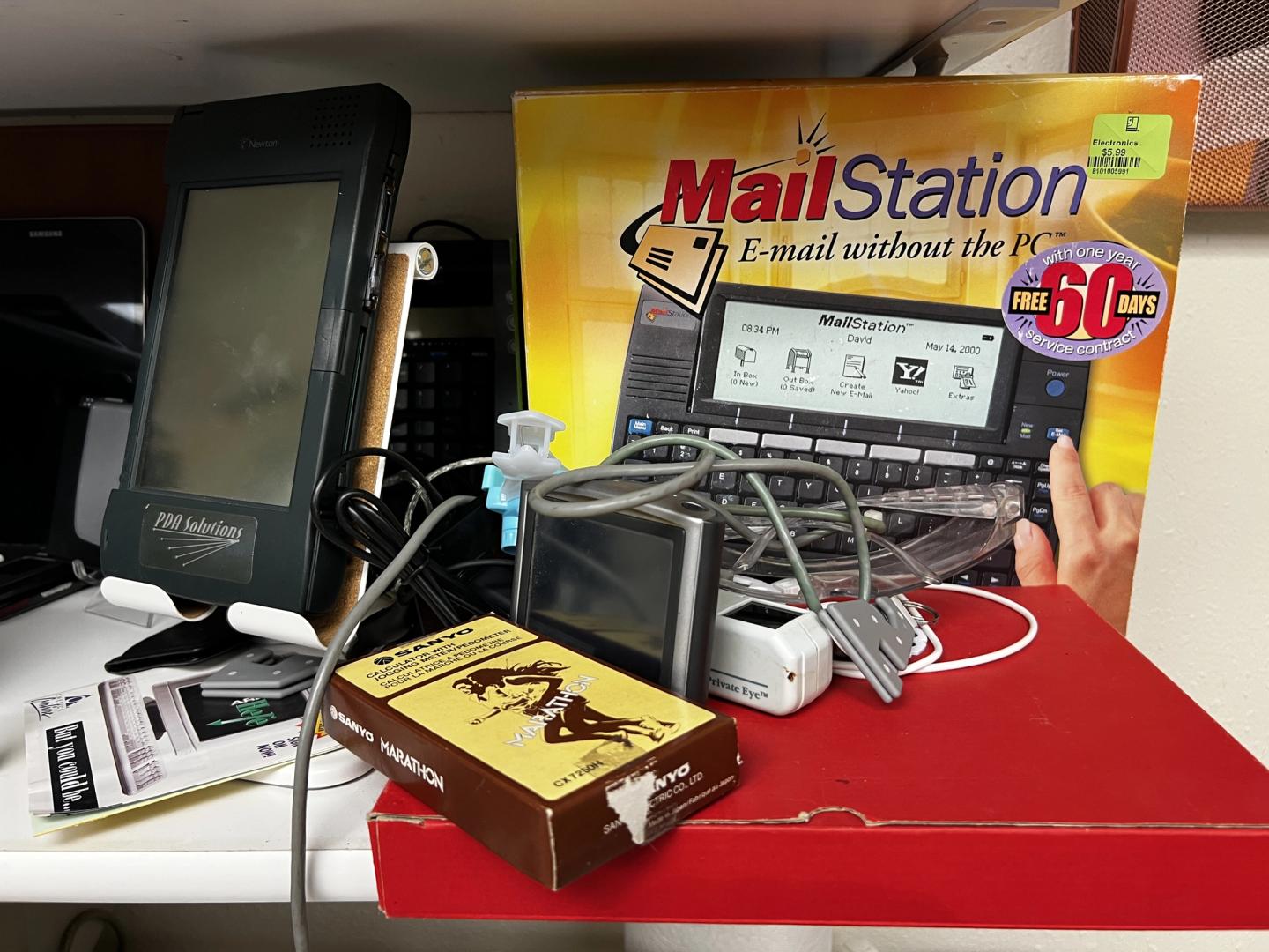 a large PDA, personal digital assistant, a Sanyo calculator with jogging pedometer, a box for Mailstation, tagline