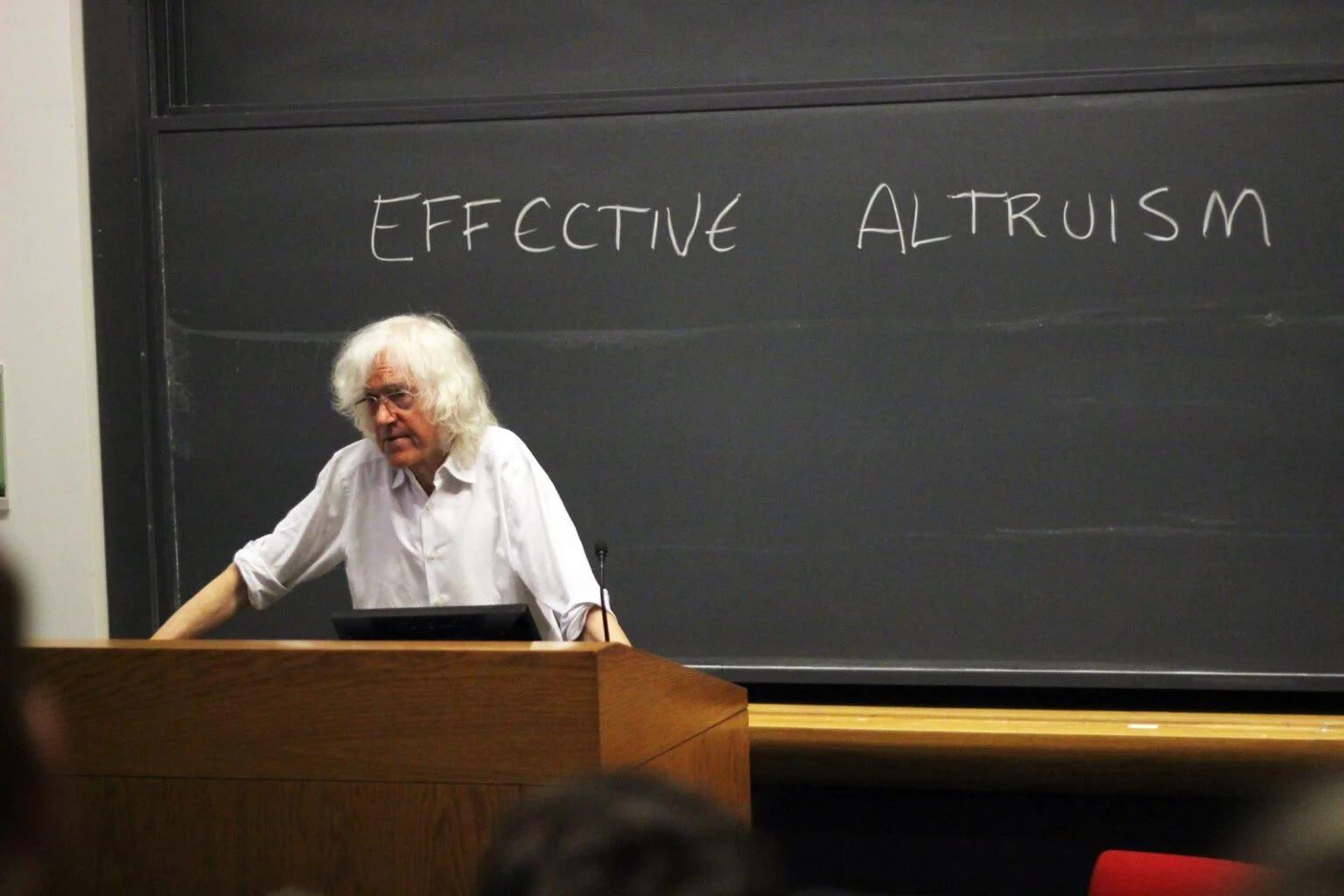 Een foto van Derek Parfit, een beroemde moraalfilosoof, die een lezing geeft over effectief altruïsme.