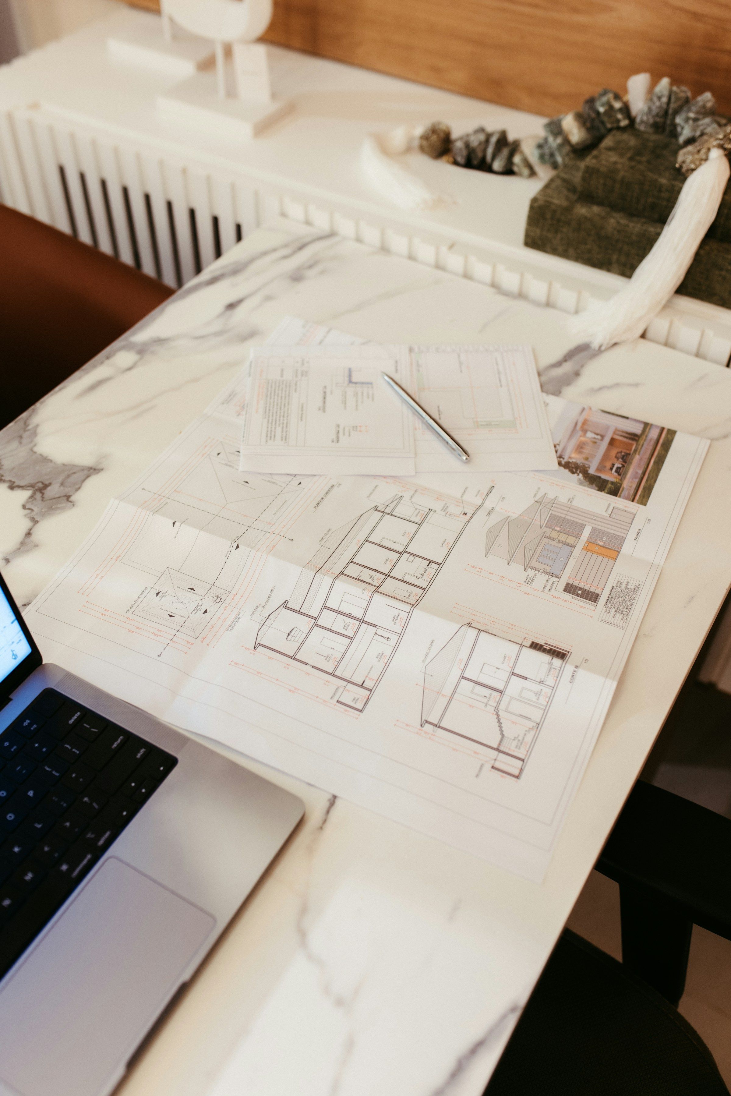 Architectural blueprints and a laptop on a marble desk