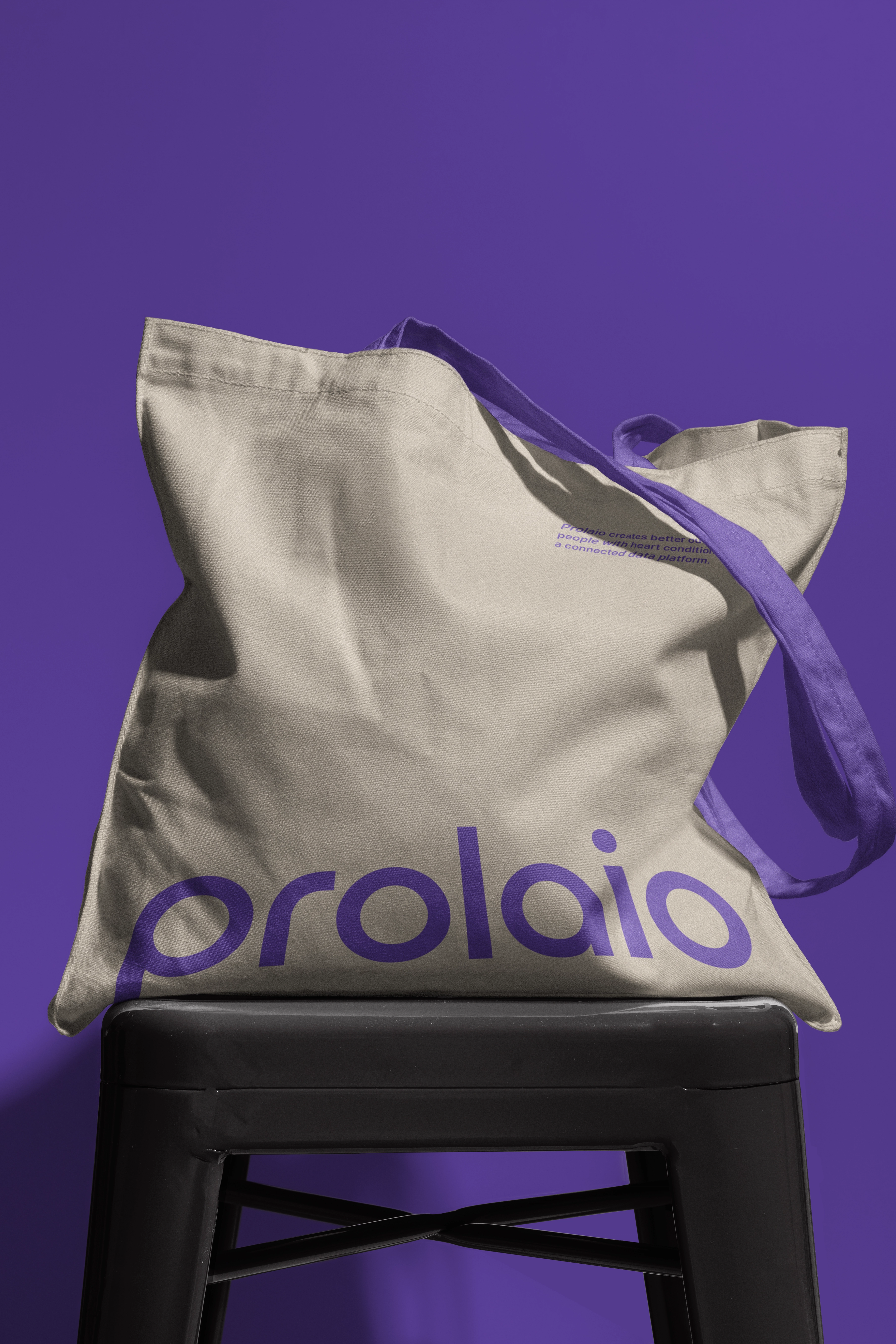 Cream tote bag with a purple Prolaio wordmark placed horizontally on the bottom of the tote bag