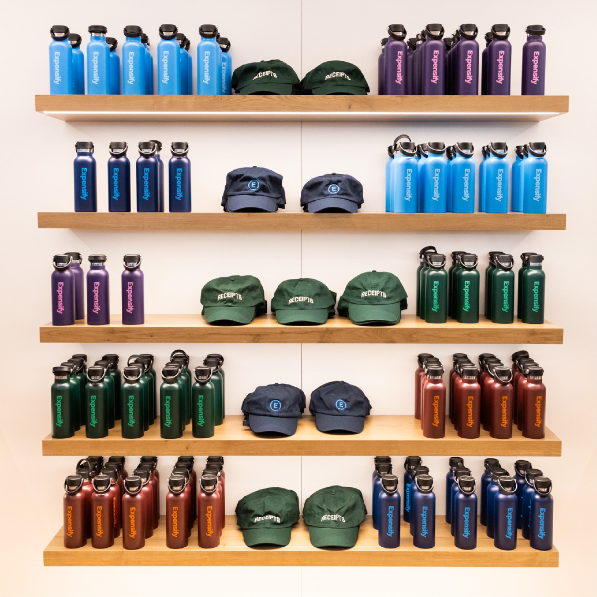 A display of Expensify branded water bottles and hats on a shelf.