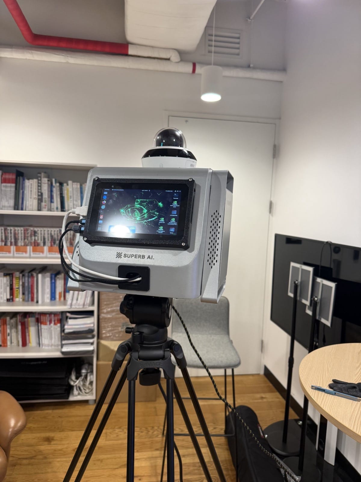 Enclosure-style mobile AI CCTV unit mounted on a tripod, with a PTZ dome camera on top and a 7-inch touch monitor on the front
