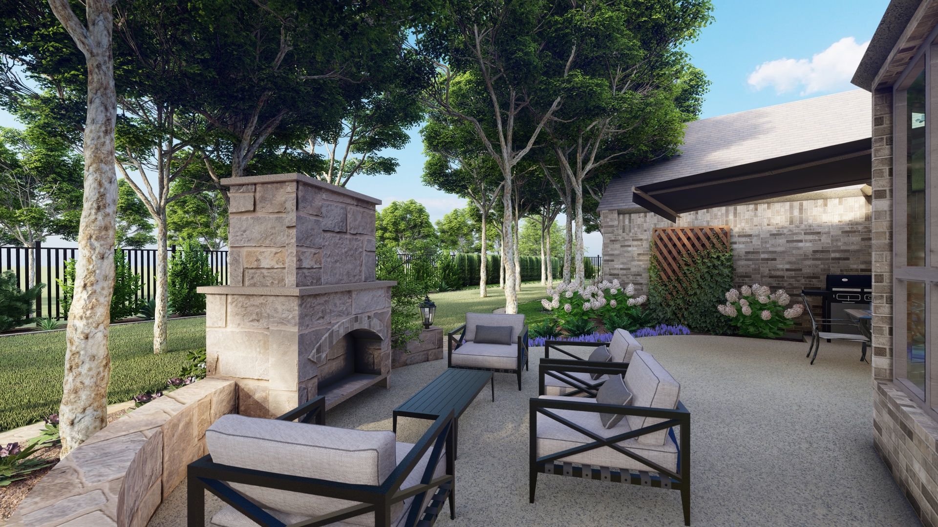 an outdoor fire place in a backyard patio just off of a stone house. beautiful lounge furniture surrounded by large trees. 