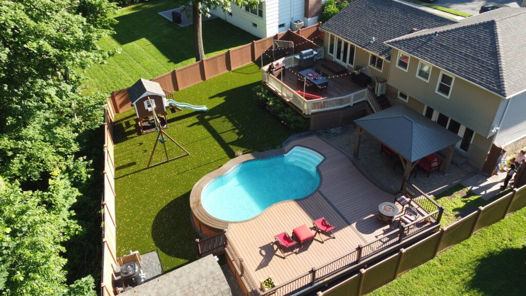 above ground pool deck and above ground pool area with trex wooden deck with flower beds, low maintenance plants and a garden
