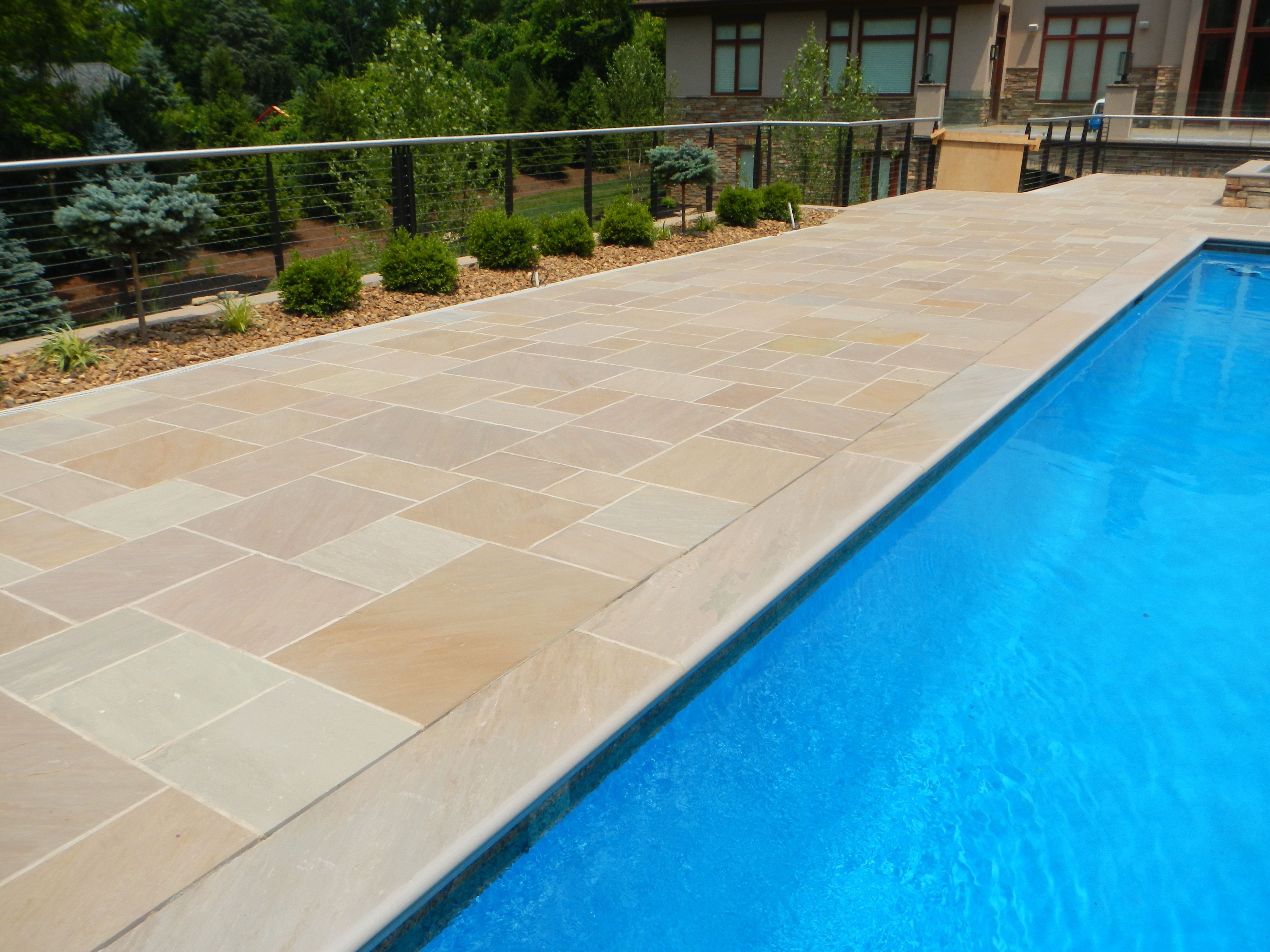 natural colors of pavers in rectangular shapes around a backyard pool 