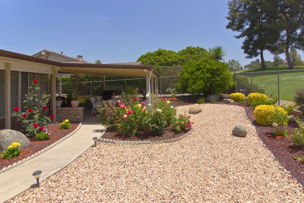 a gravel yard with flower beds around it