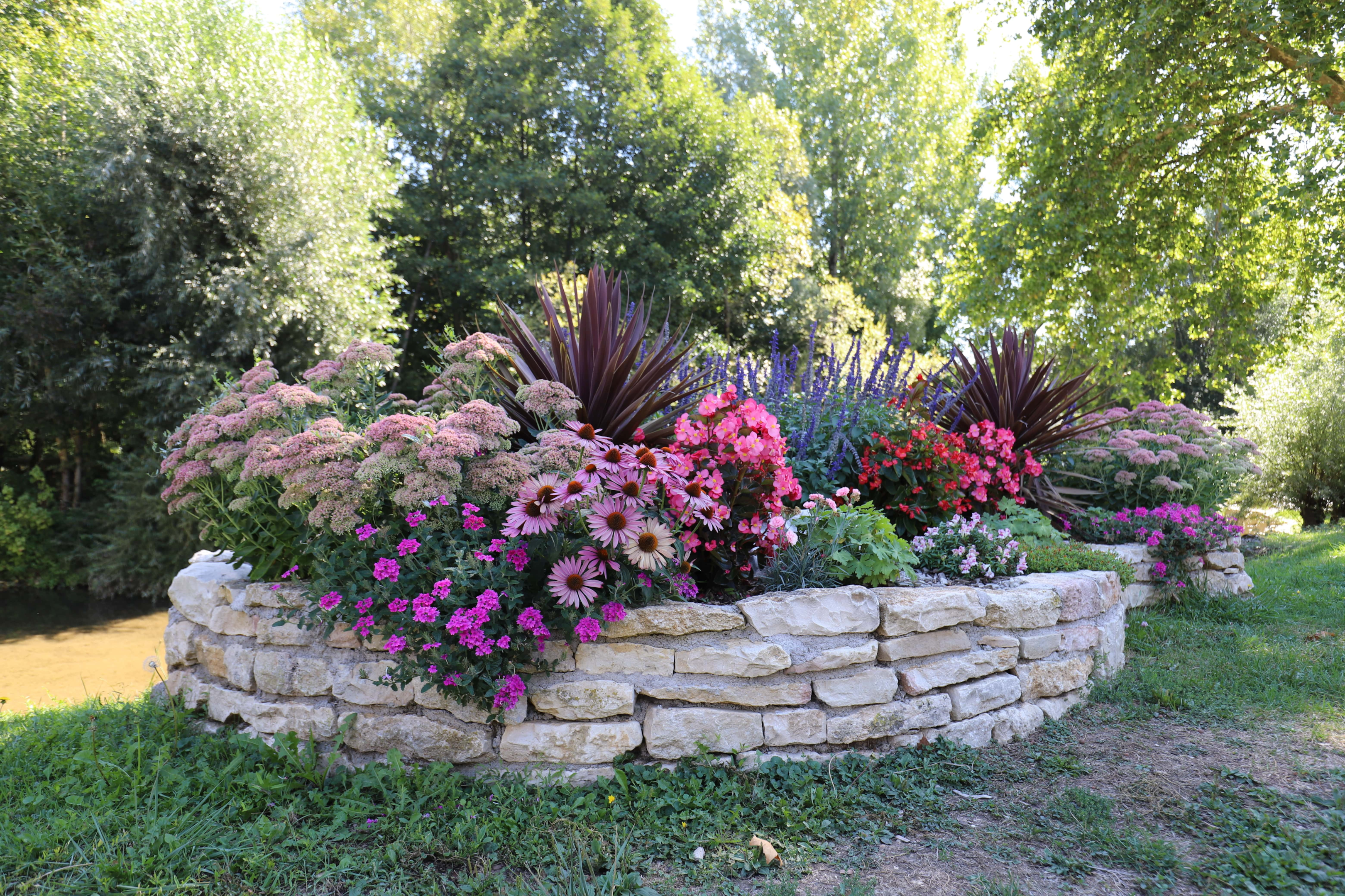 a natural stone wall around a garden bed in the middle of a yard
