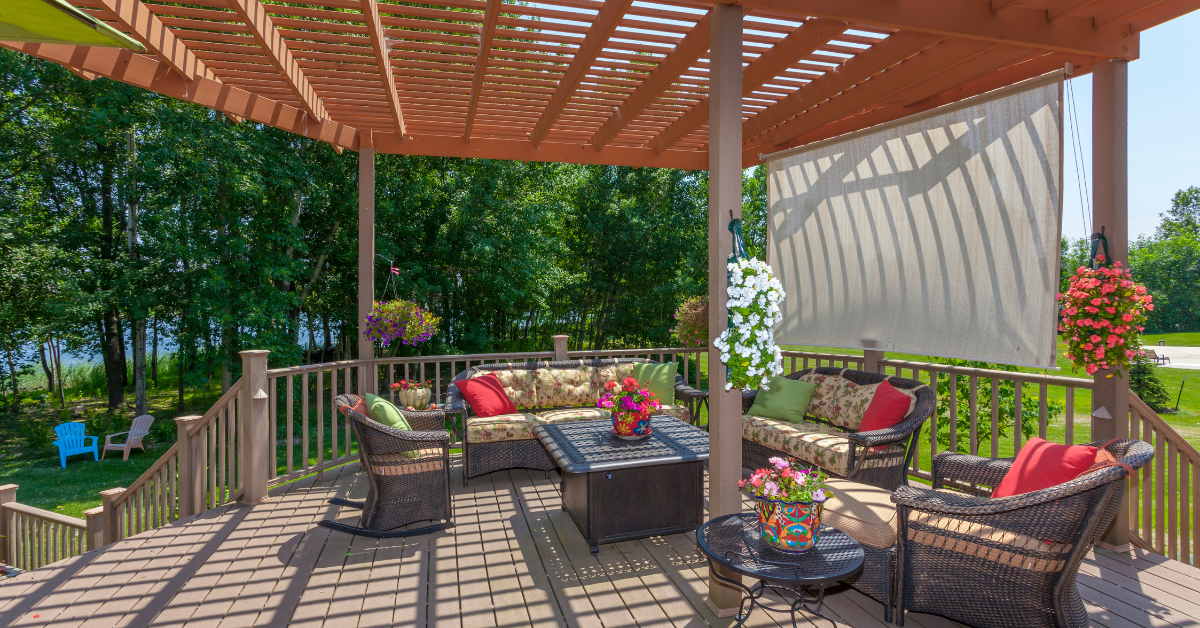 seating under a pergola with curtains to add shade on a backyard deck