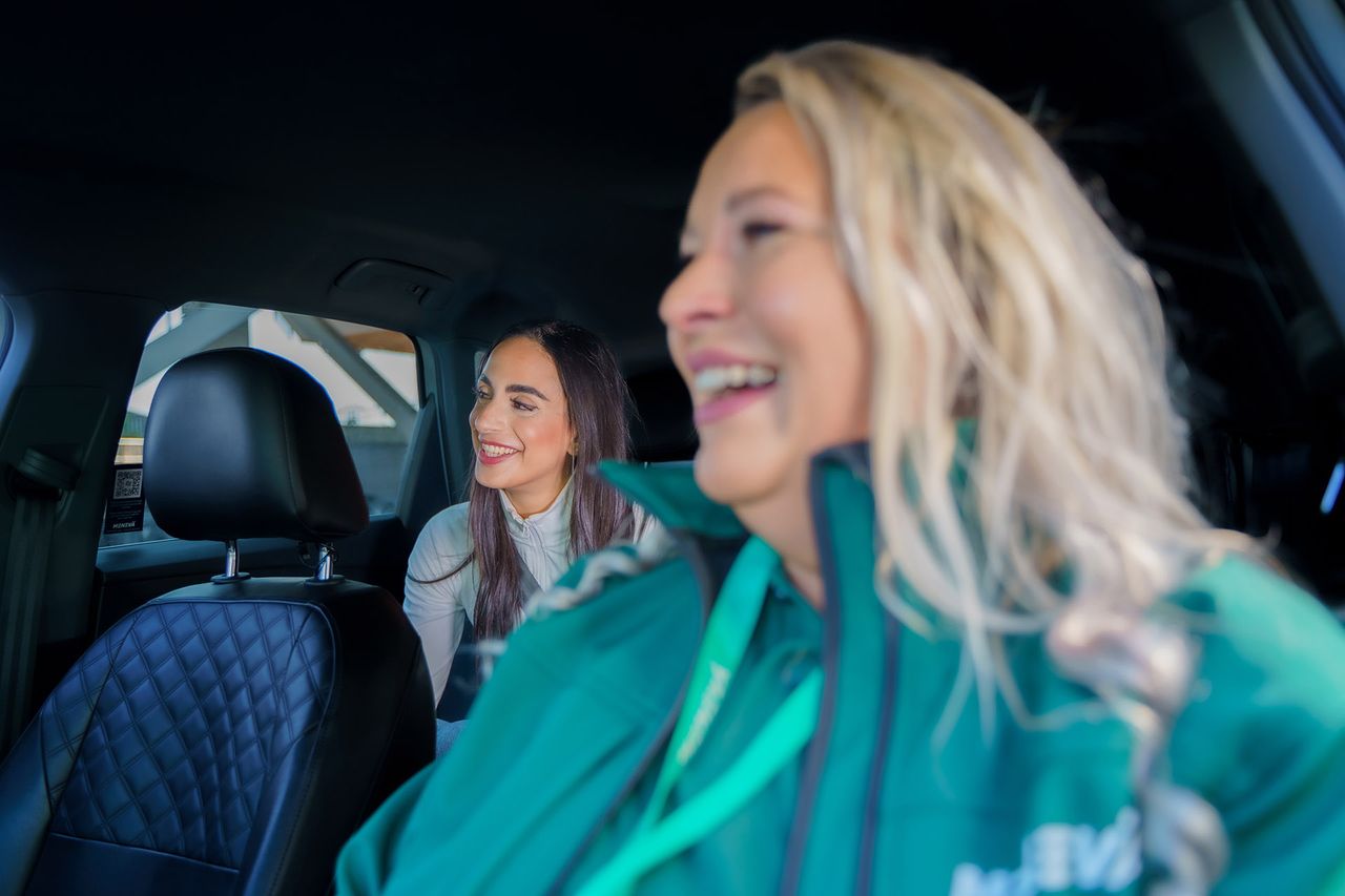 A smiling Menevä host talking with a customer inside the car