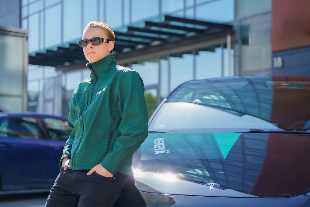 Vihreätakkinen ja aurinkolasipäinen Menevä-host nojaa autoon