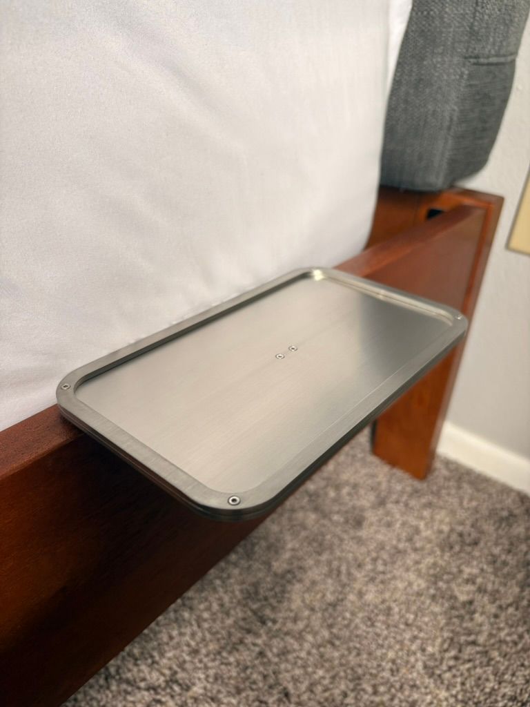 Silver metal bed shelf mounted beside a bed