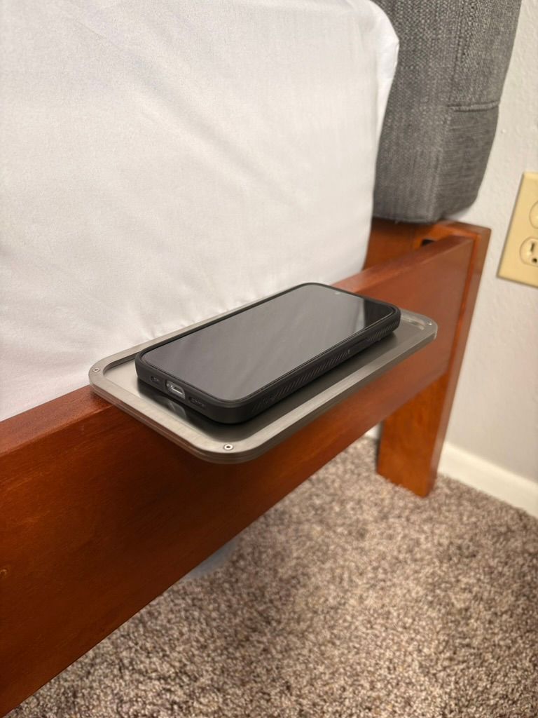 Silver metal bed shelf holding a phone