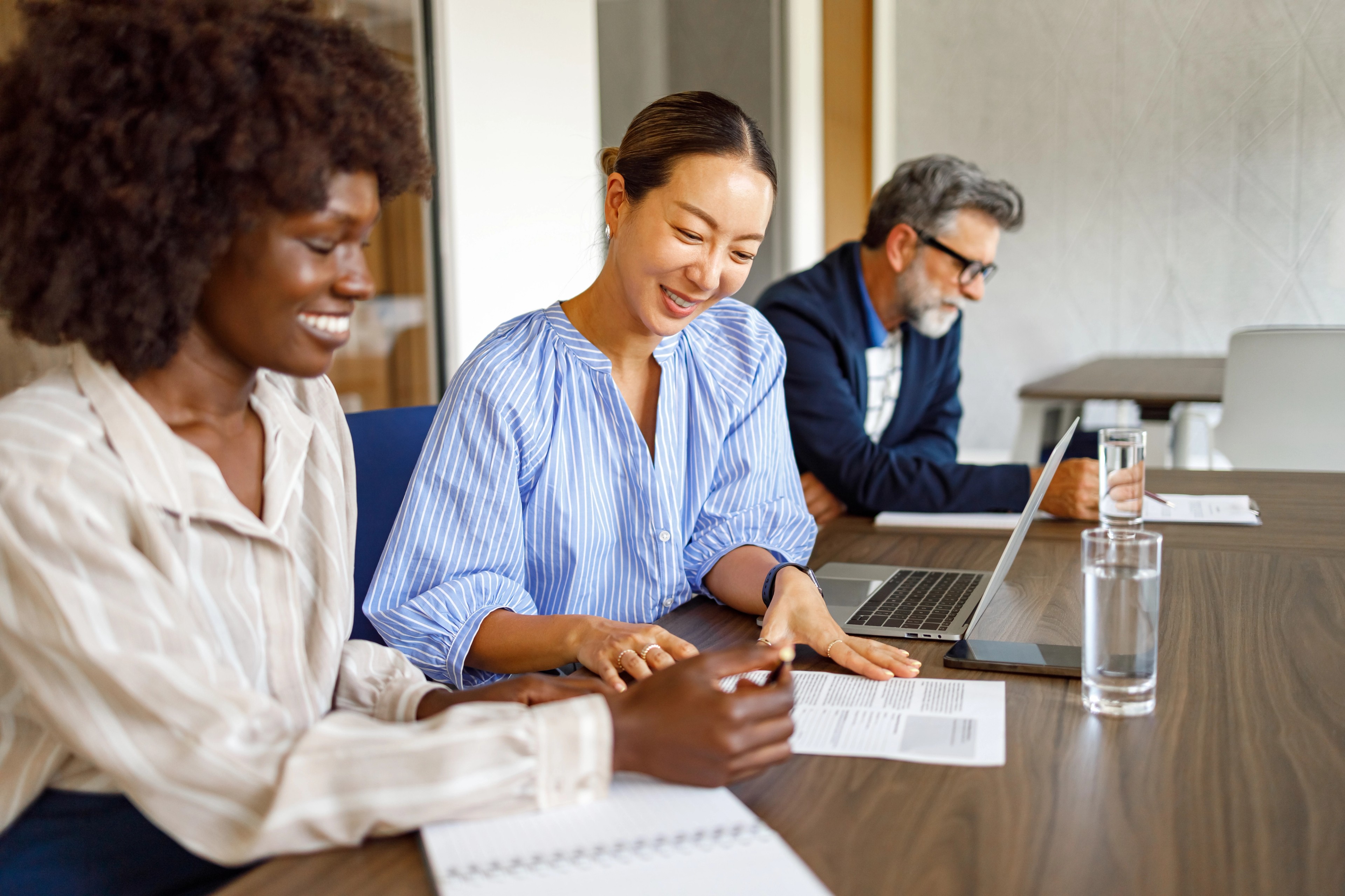 Three public sector colleagues review digital accessibility compliance documents together at a meeting room table