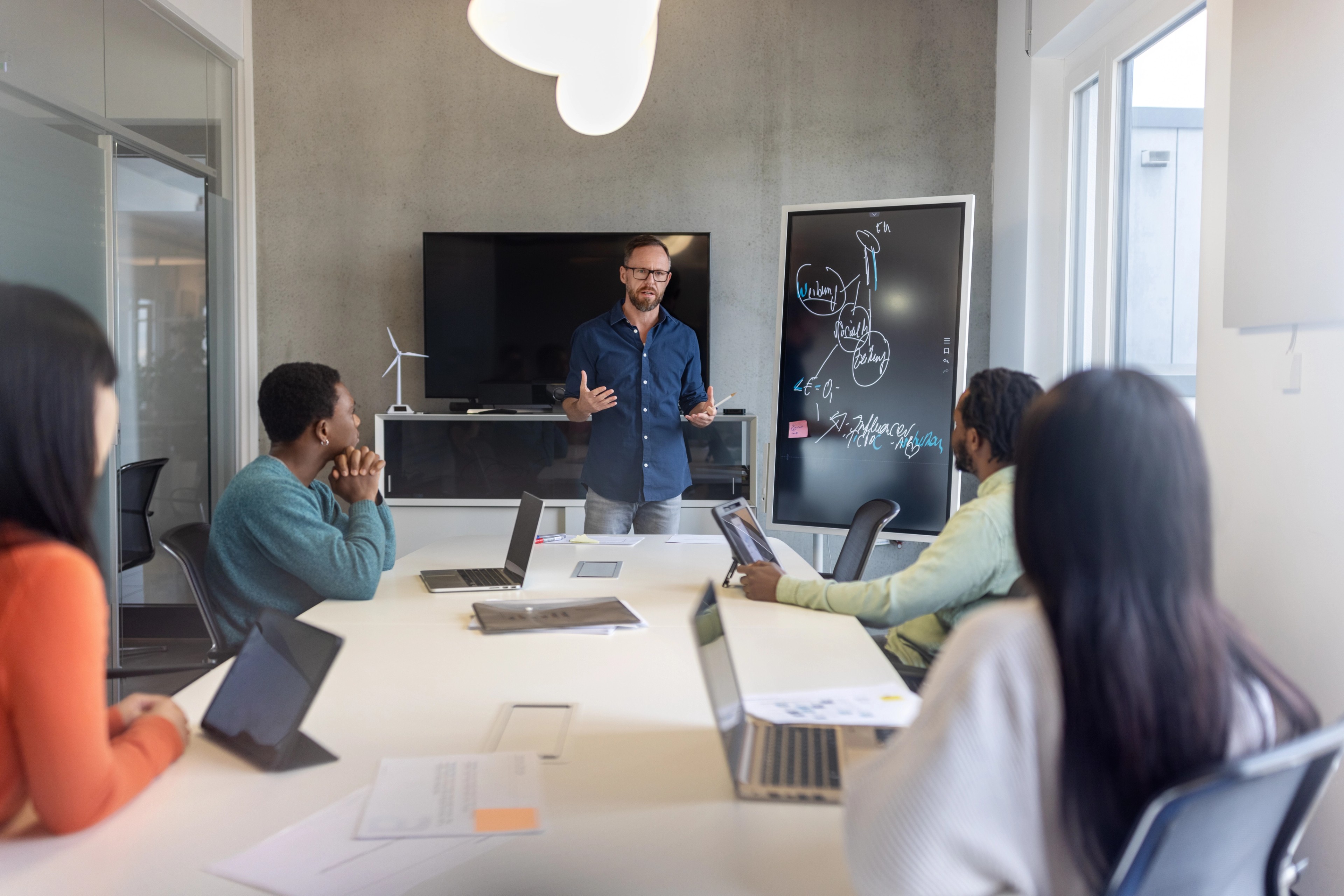 Mature businessman explaining project details to colleagues sitting at conference room