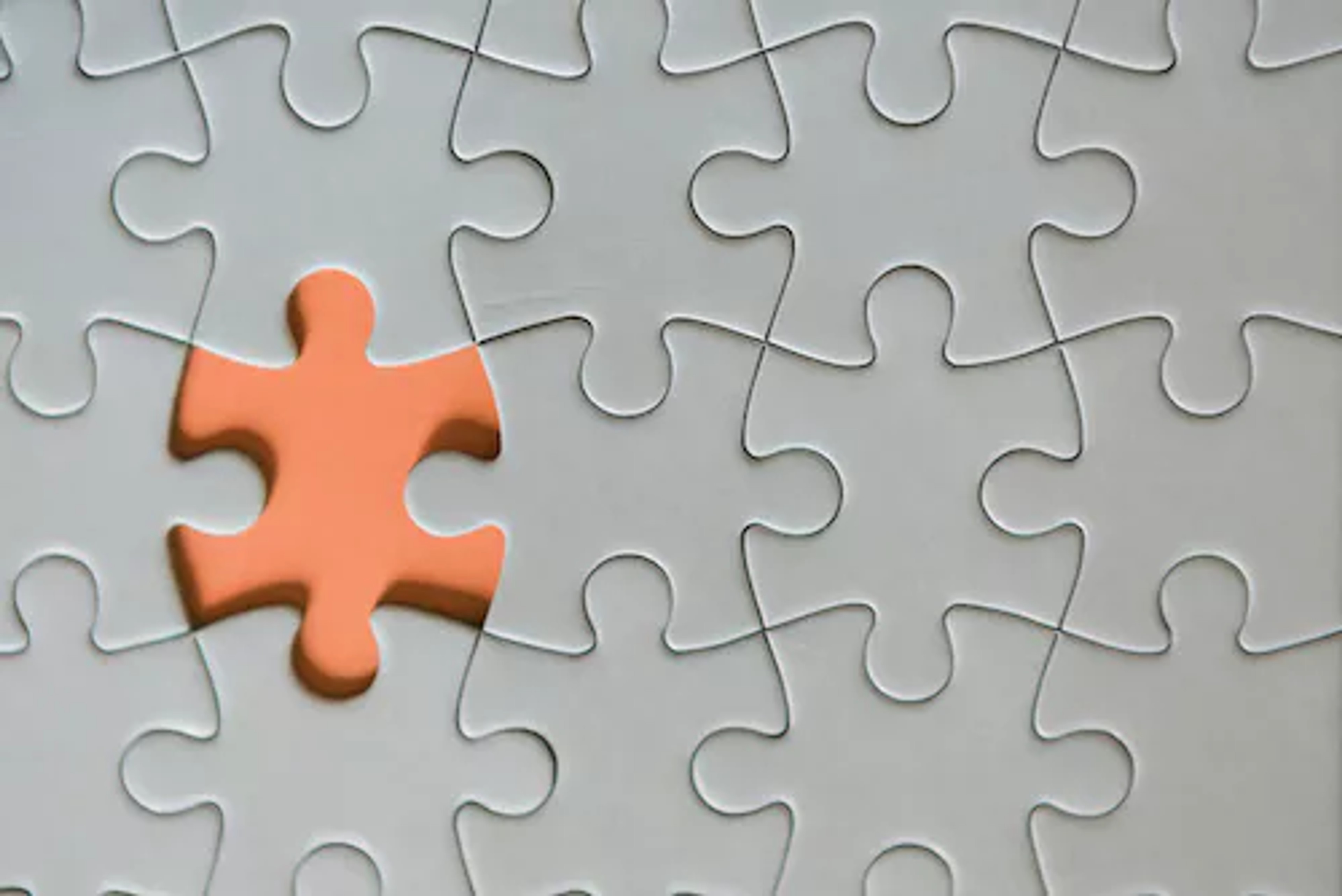 Picture of a grey puzzle with one orange piece