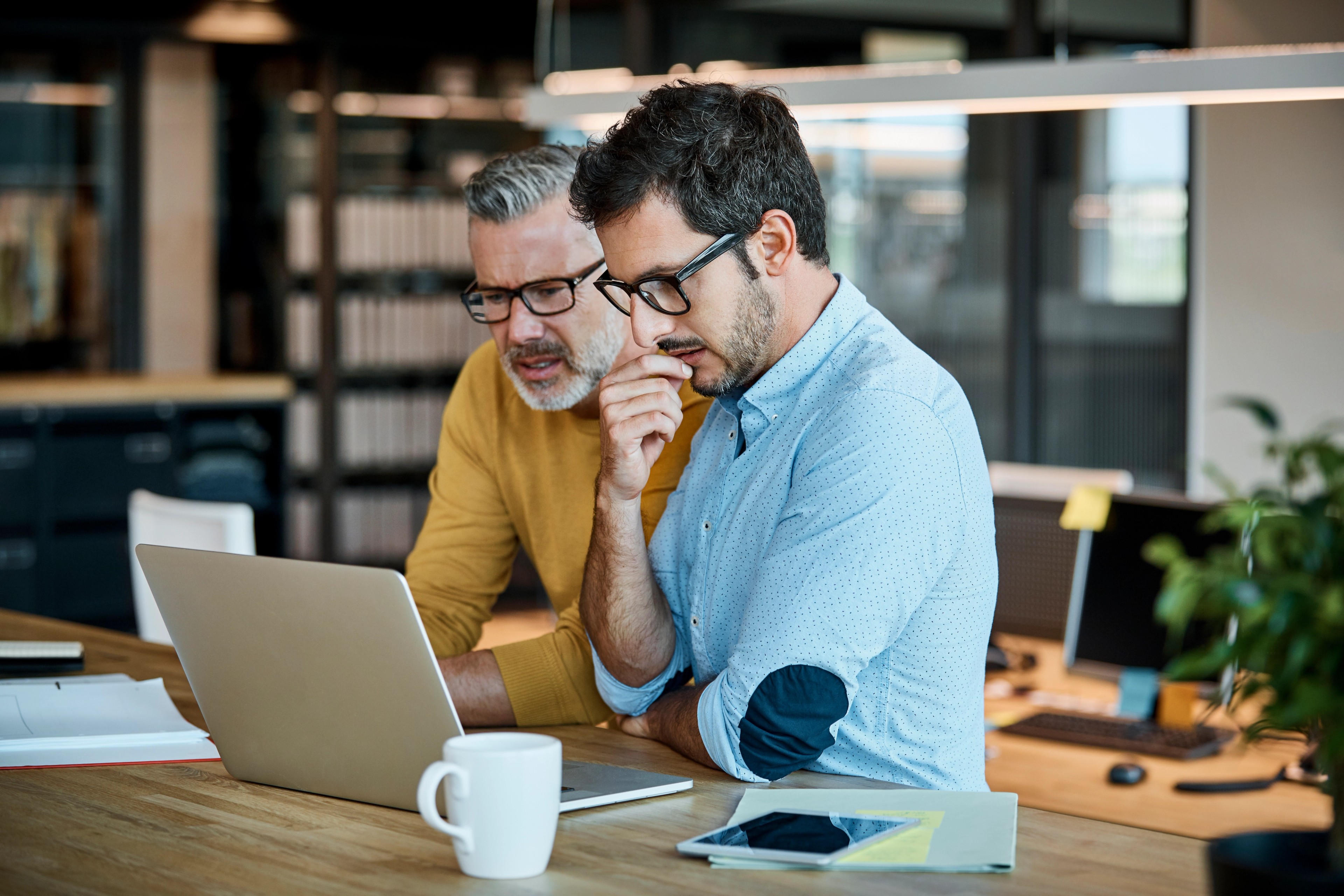 Businessmen using laptop together at desk