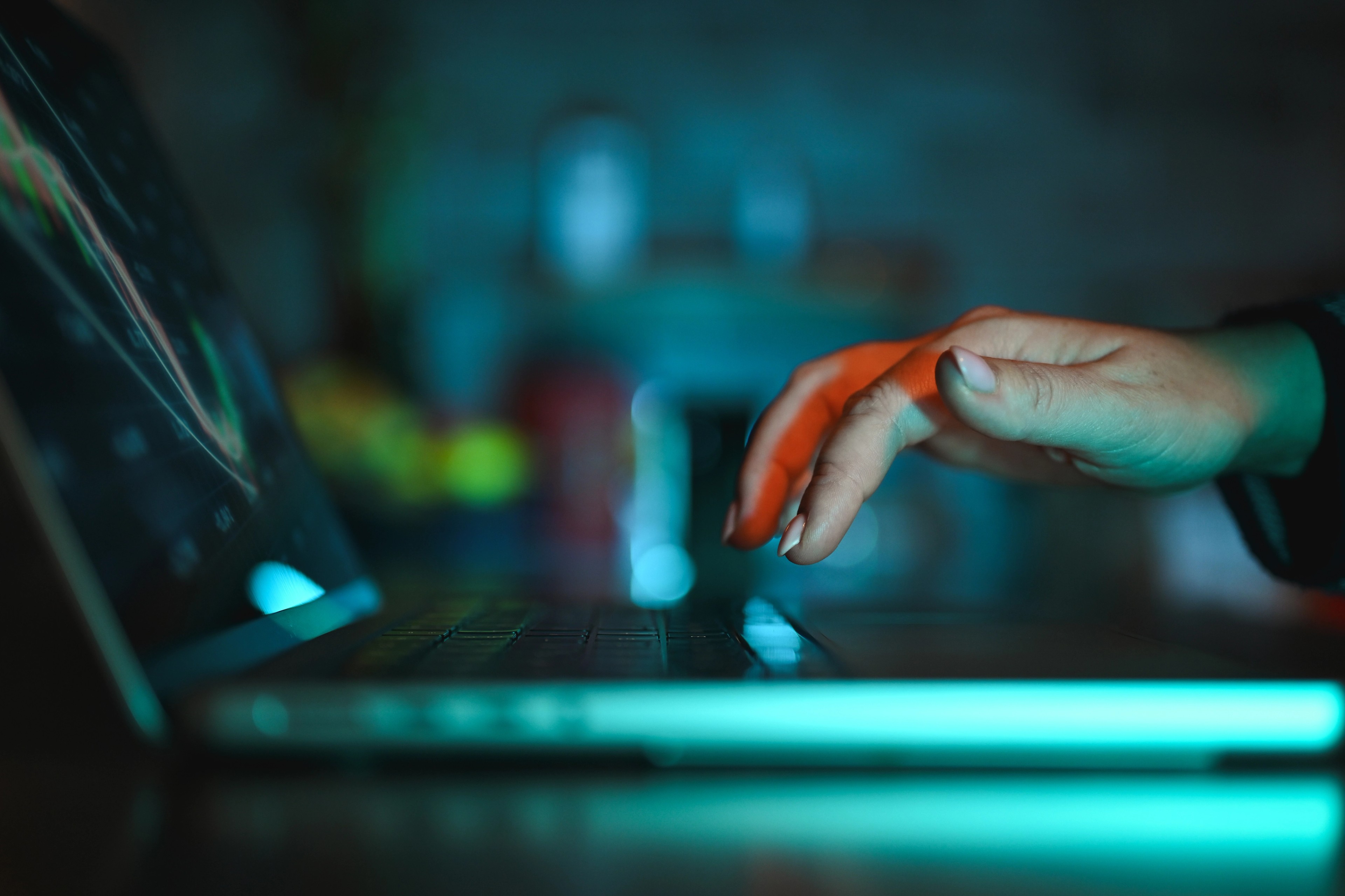 Close-up of a hand reaching toward a laptop keyboard, representing the hidden access pathways and third-party risks that can expose organisations to cyber threats.