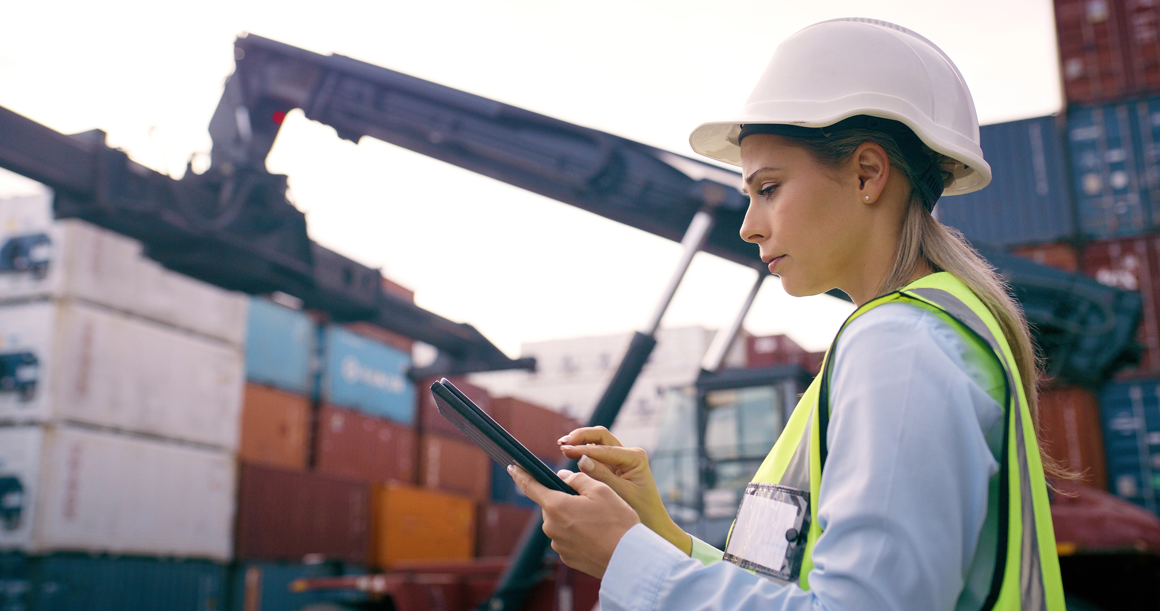 Tablet, containers and logistics worker by crane for heavy loading with global product trade at freight port. Technology, supply chain and female distribution planner with cargo stock for shipping.