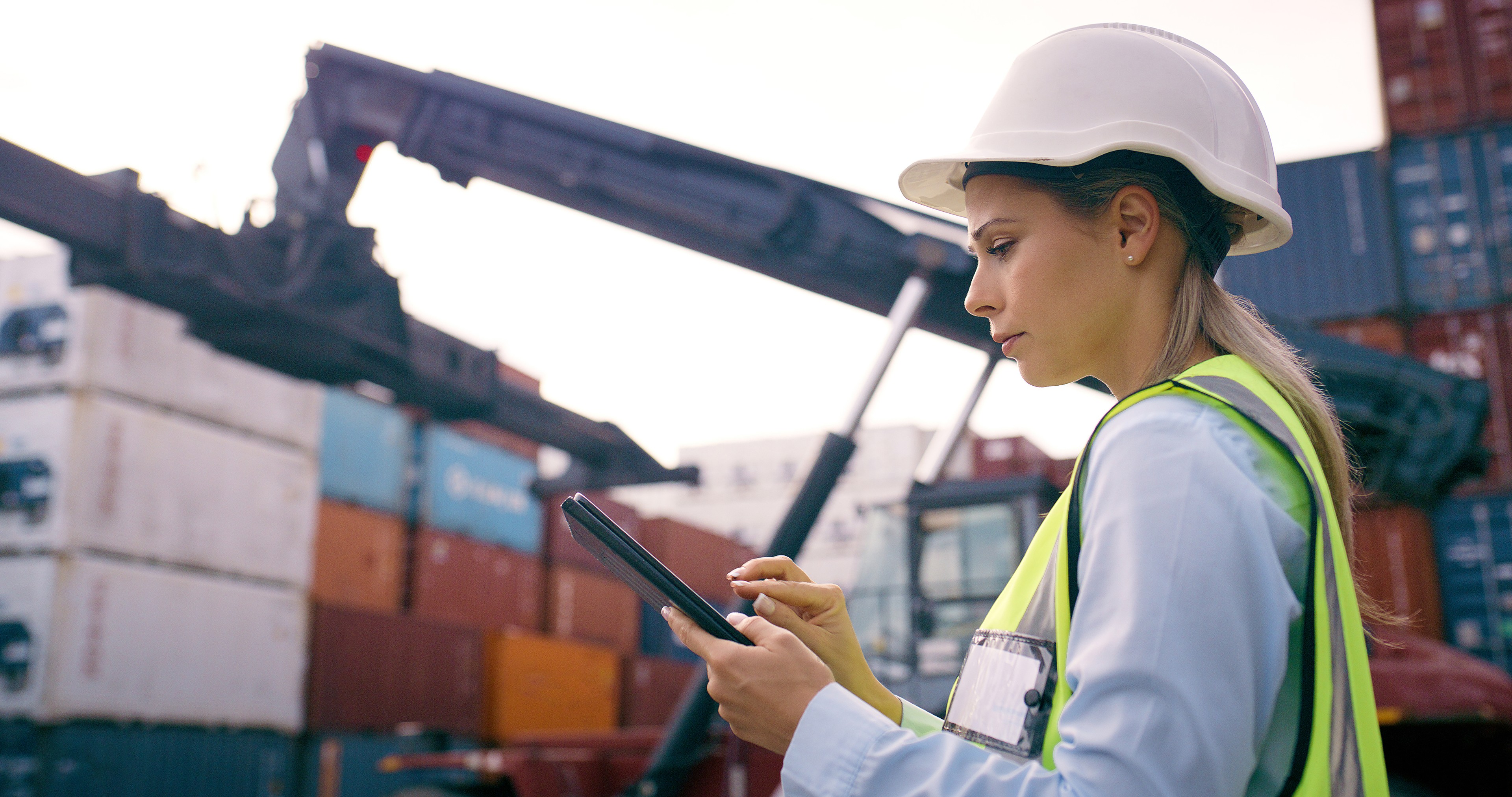 Tablet, containers and logistics worker by crane for heavy loading with global product trade at freight port. Technology, supply chain and female distribution planner with cargo stock for shipping.