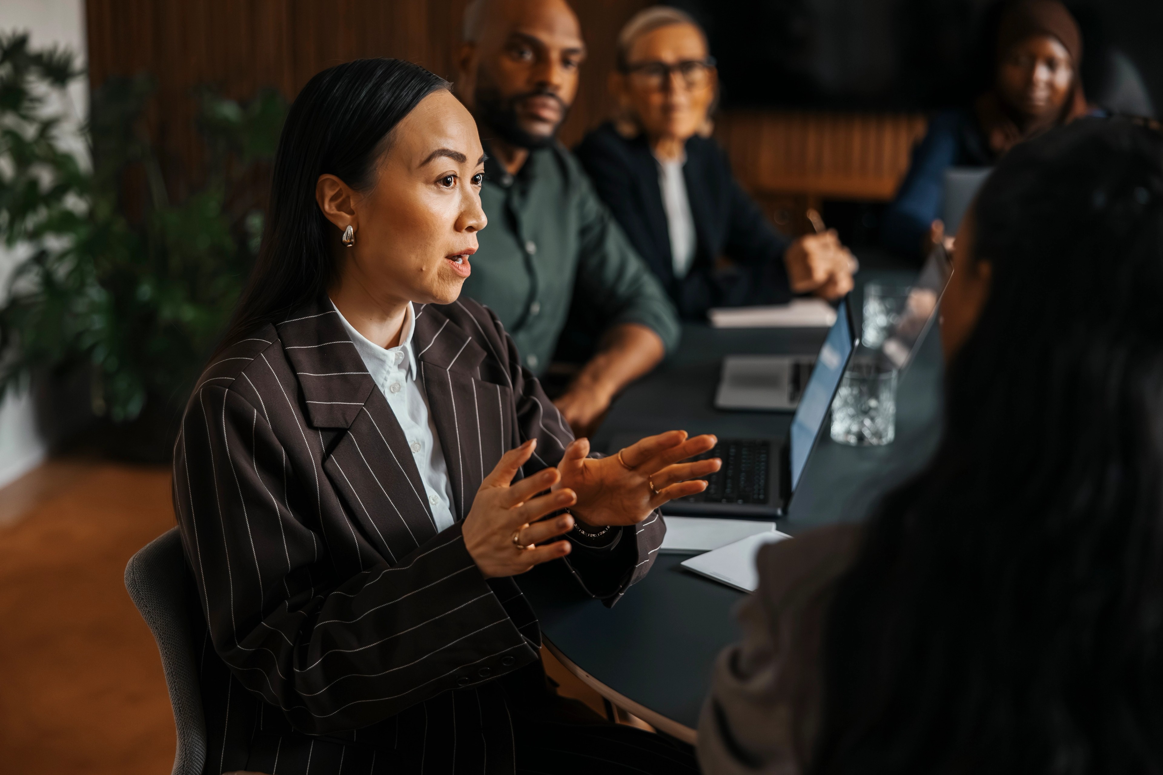 Business professionals meeting around a conference table while discussing governance, compliance and corporate filing responsibilities.