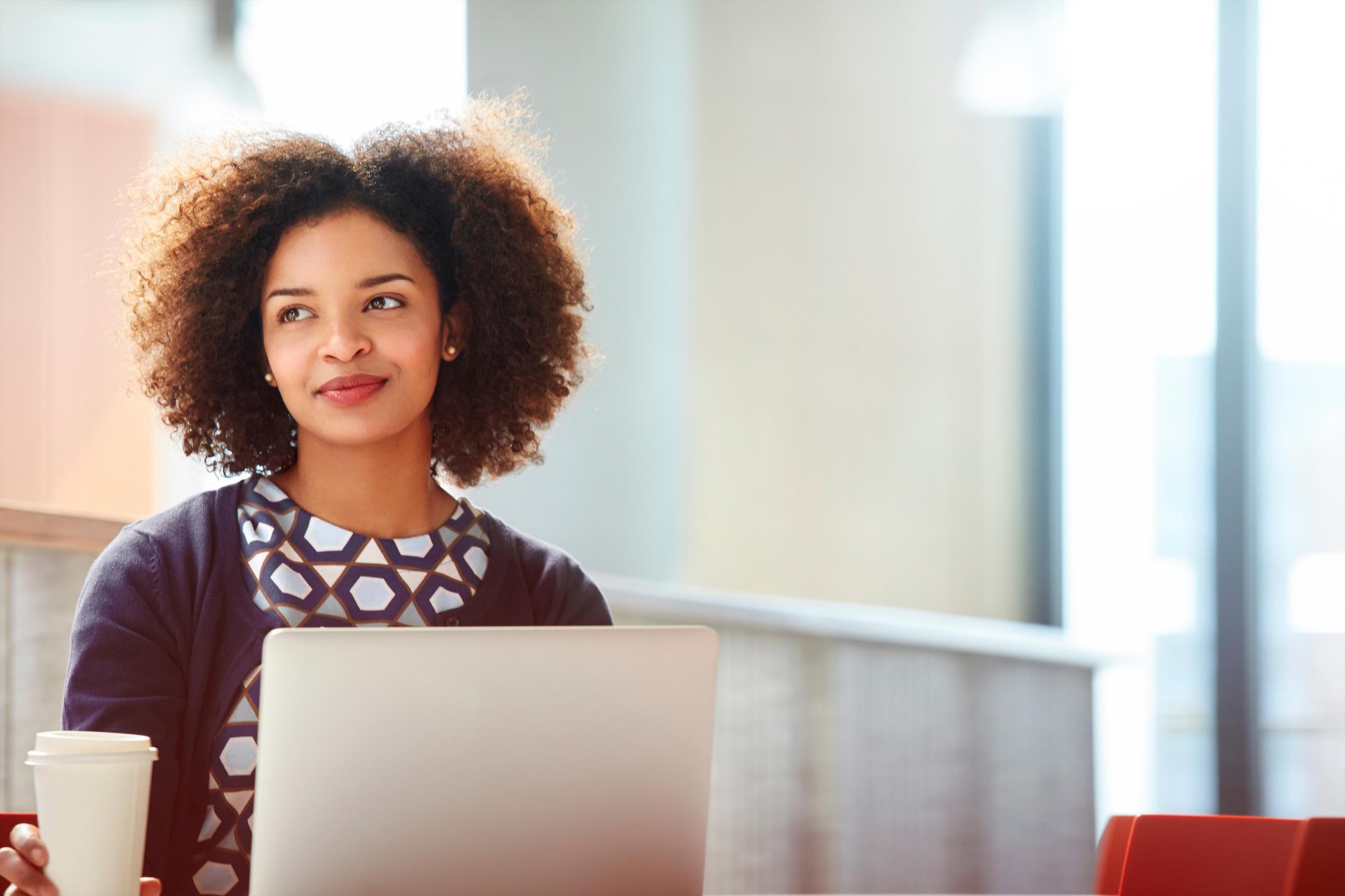 CISO gazes out of an office window, holding a laptop, after earning an elevated board role
