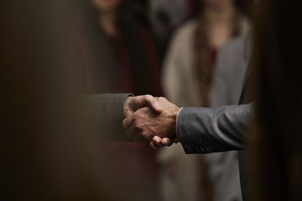 two men shaking hands in a dark room