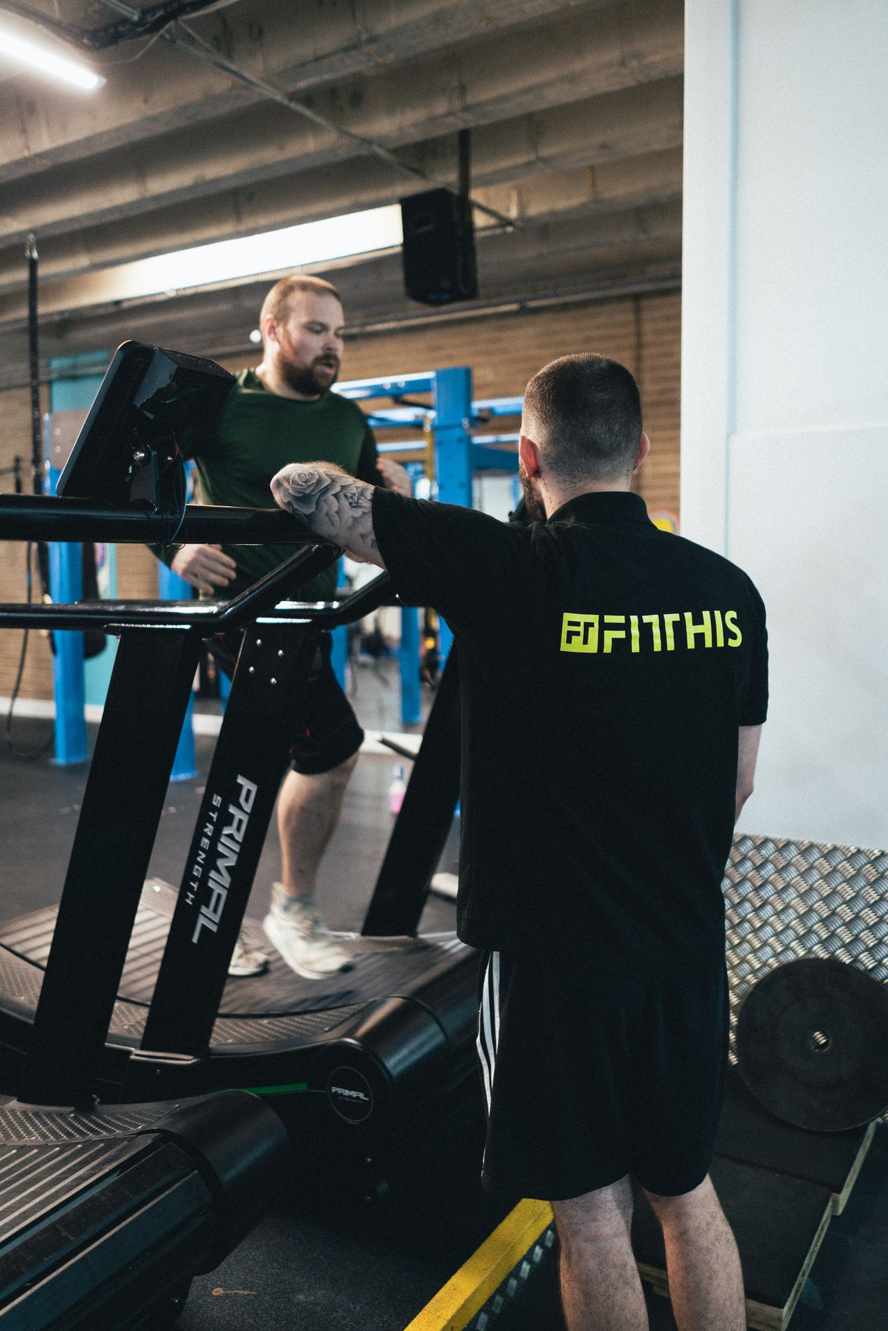 A trainer checking in with a member running on the treadmill
