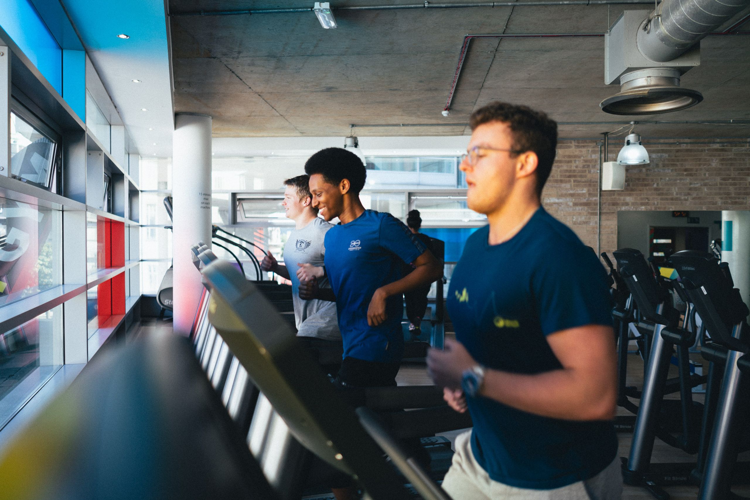 Members running on the treadmills beside the front windows at Fit This