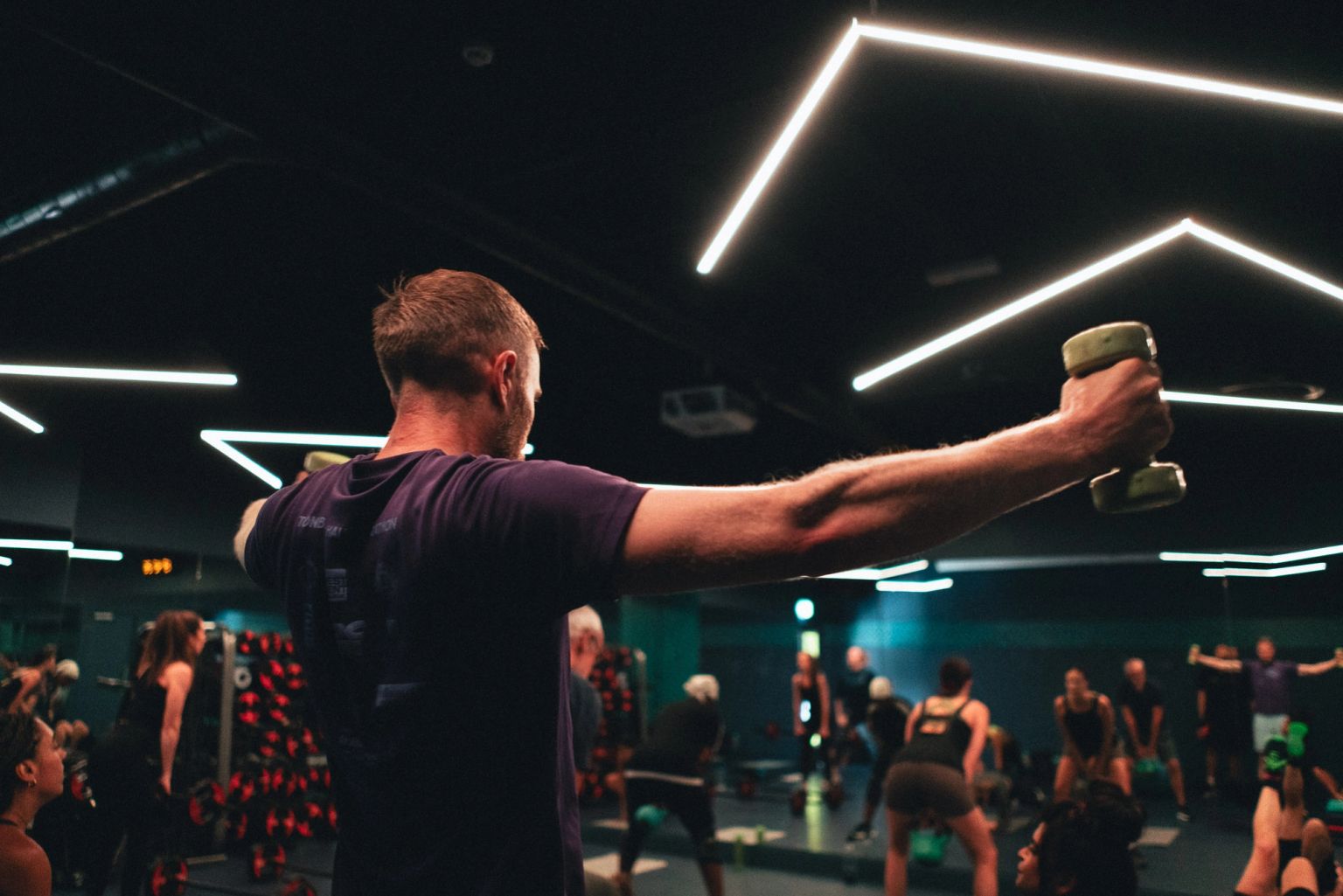 Members lifting dumbbells together in a class at Fit This