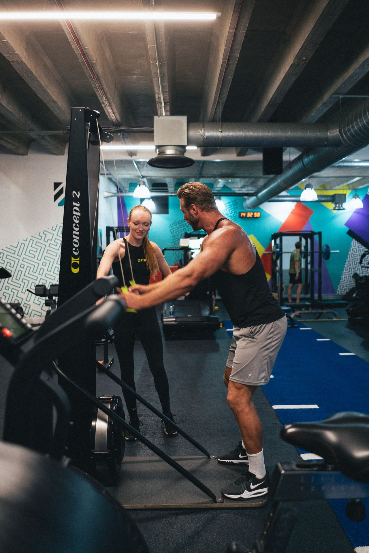 A trainer coaching a member on the Concept2 machine