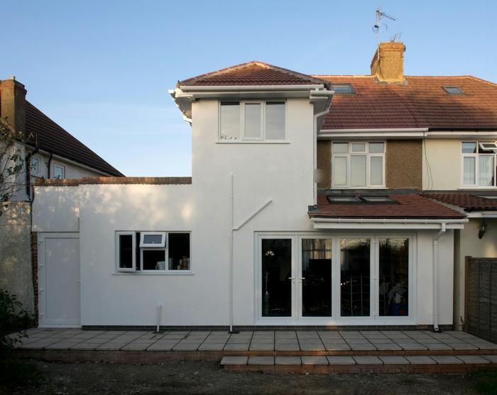 The finished rendered rear extension of a semi-detached house, with French doors opening onto a patio.