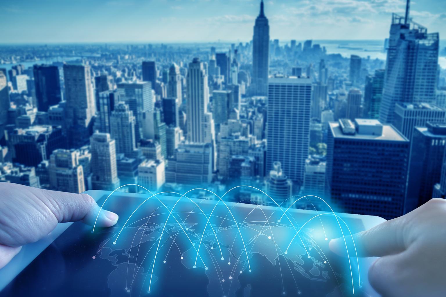 Hands holding a tablet displaying a cityscape against a vibrant skyline background.