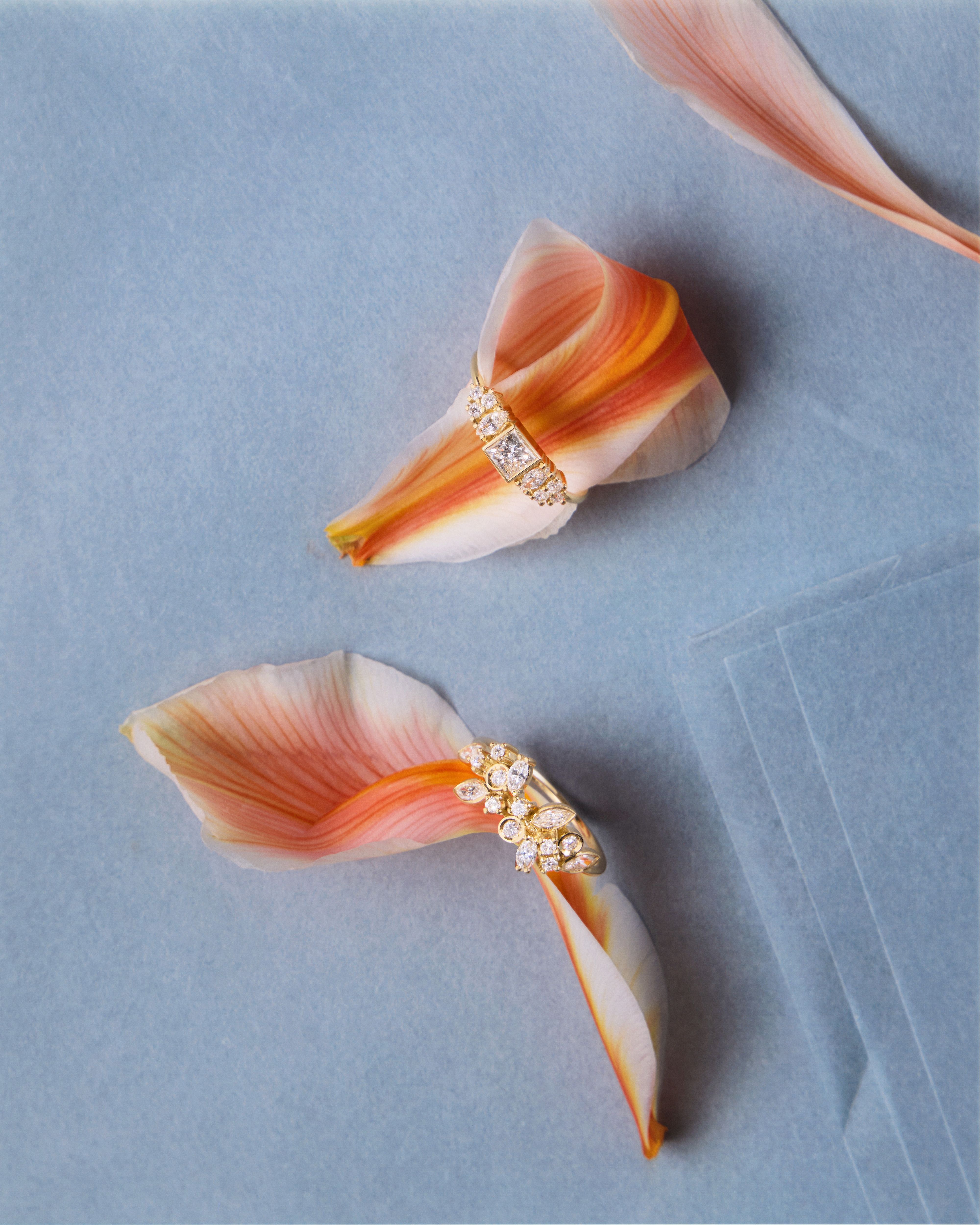 photographie papier bleu avec pétales oranges et deux bagues Sophie d'Agon | © Studio Cent-Huit 2025