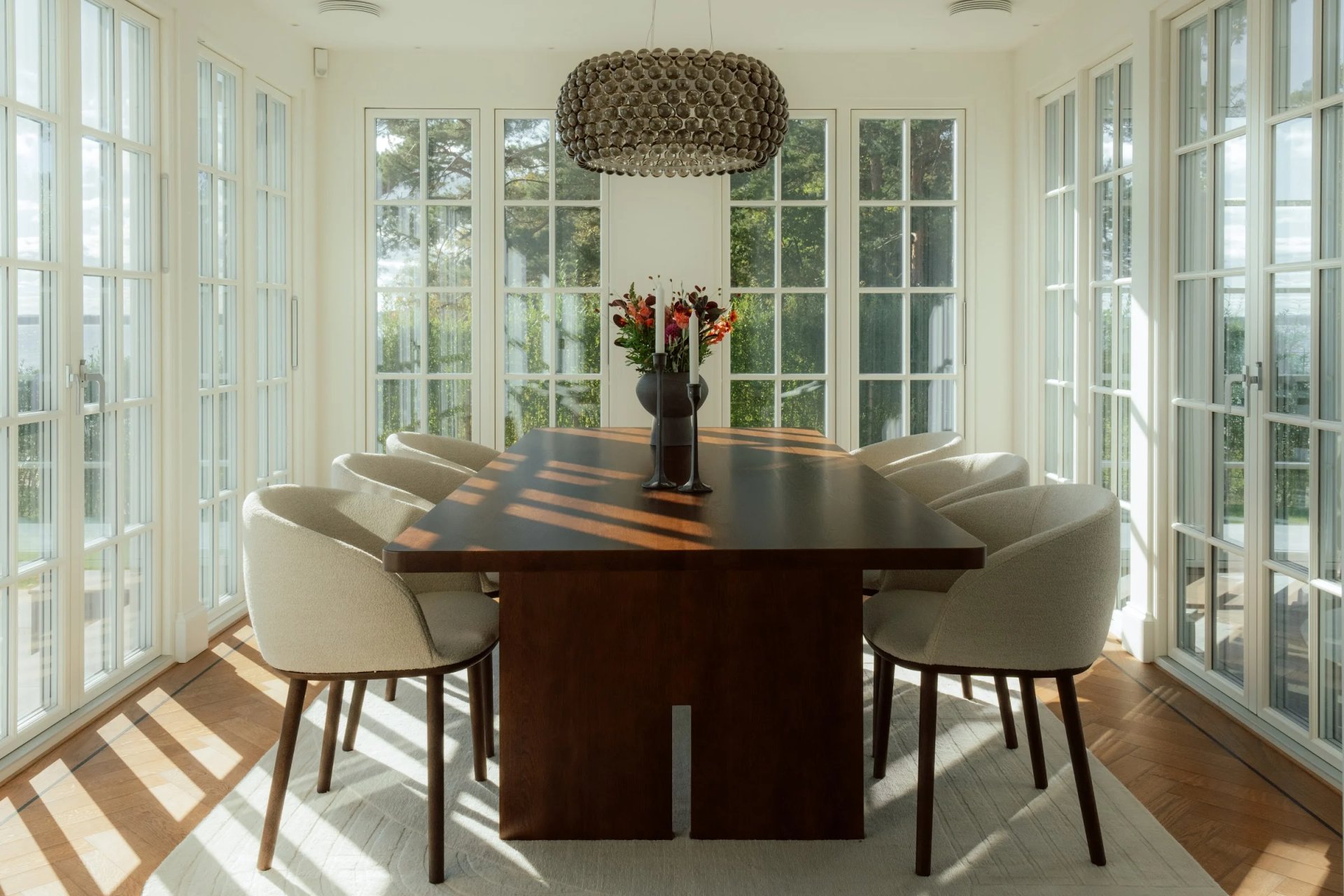 Dining table surrounded by tall windows at Villa Sand