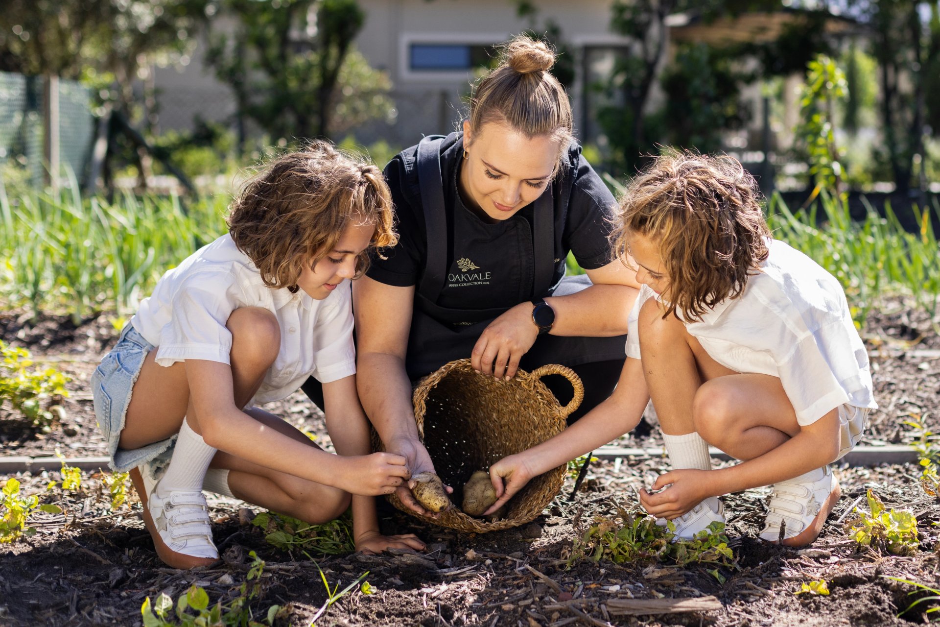 Children gathering vegetables with an Oakvale team member in the garden