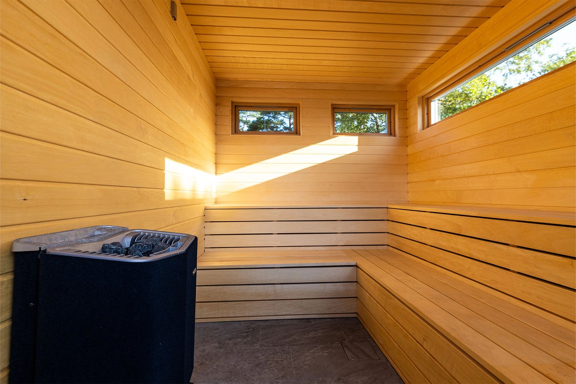Wood-lined sauna with sunlight across the benches at Villa Sand