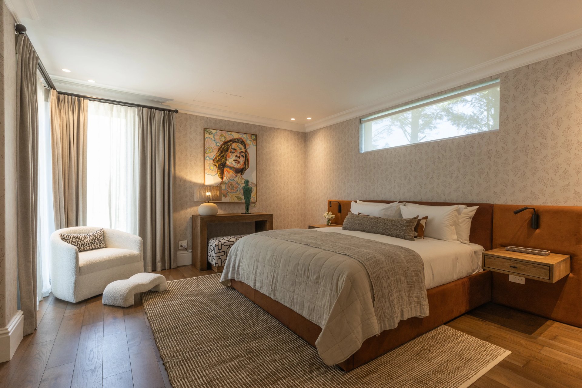 Bedroom with leather headboard, framed art and a garden outlook