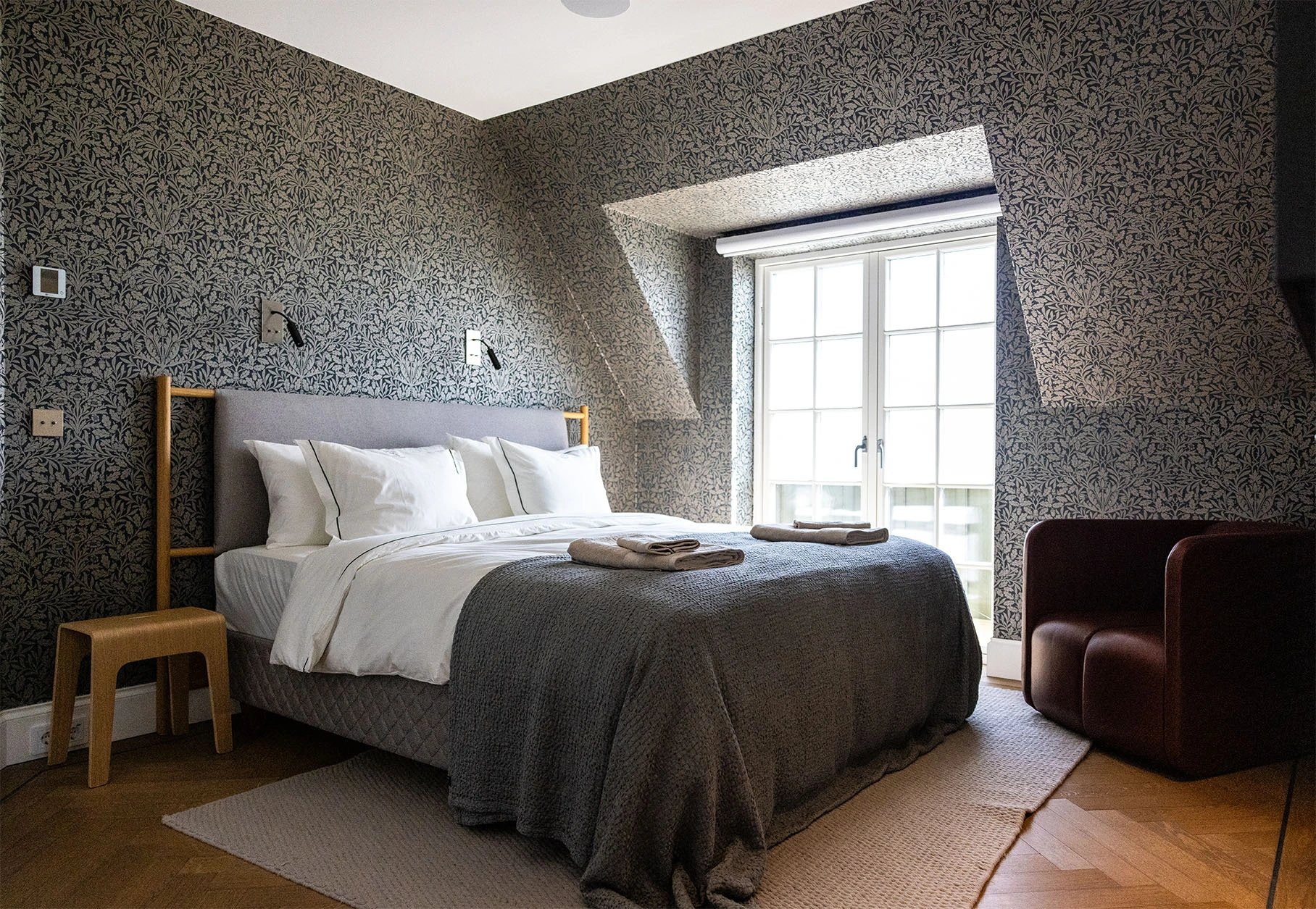 Double bedroom with patterned walls and a window at Villa Sand