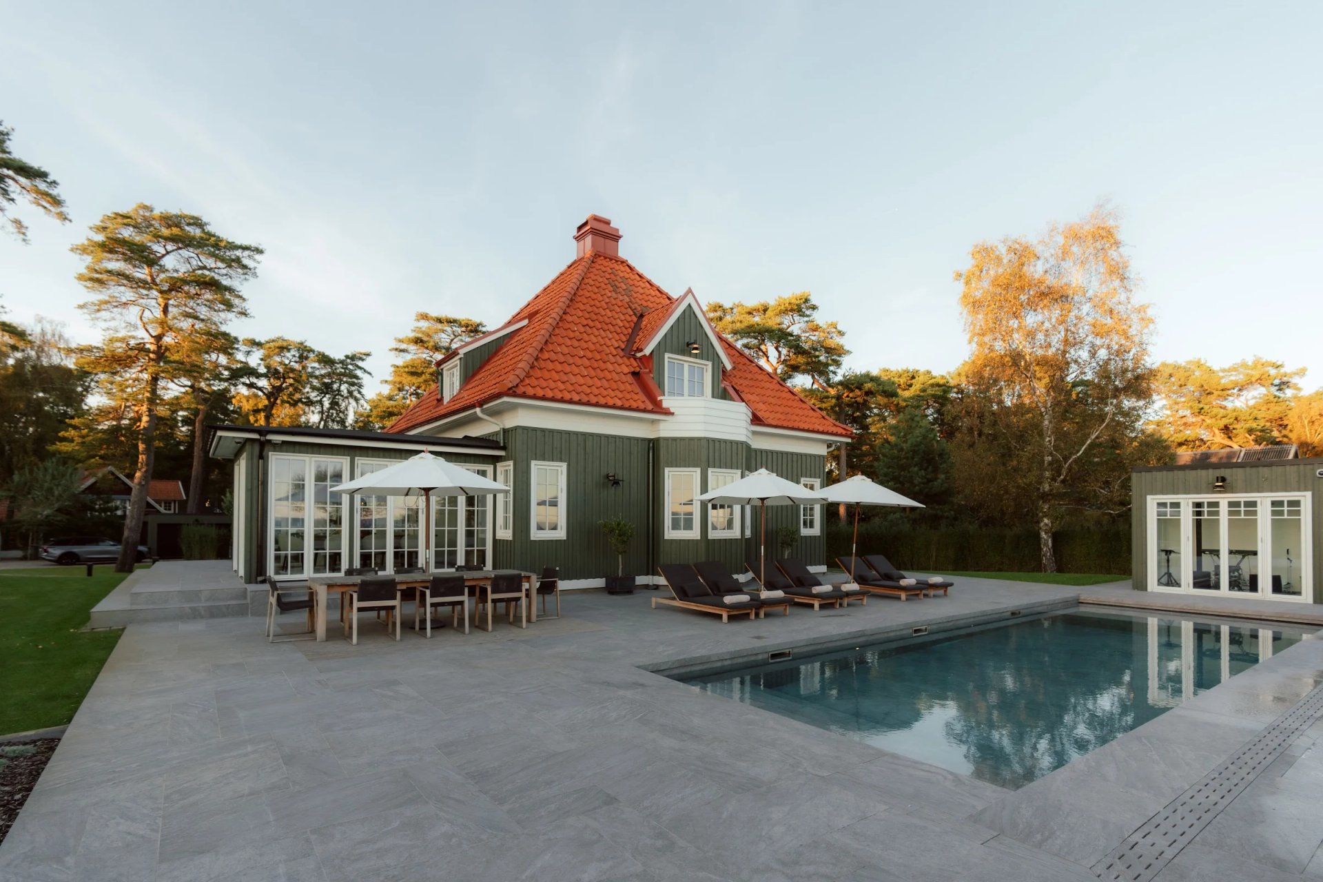 Villa Sand’s green timber house, red tiled roof and swimming pool