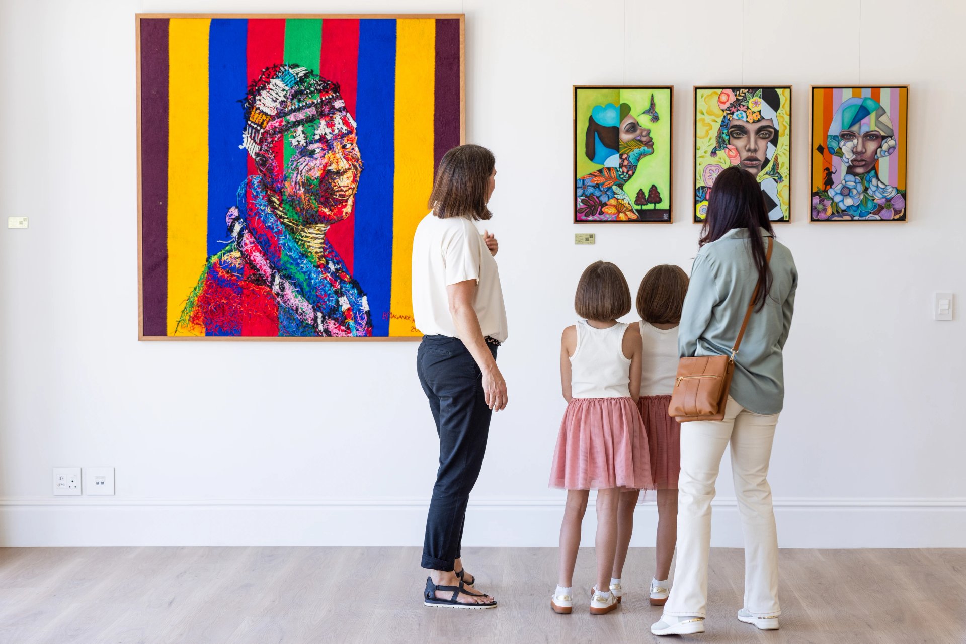 A family viewing colourful artworks in the Oakvale Estate gallery