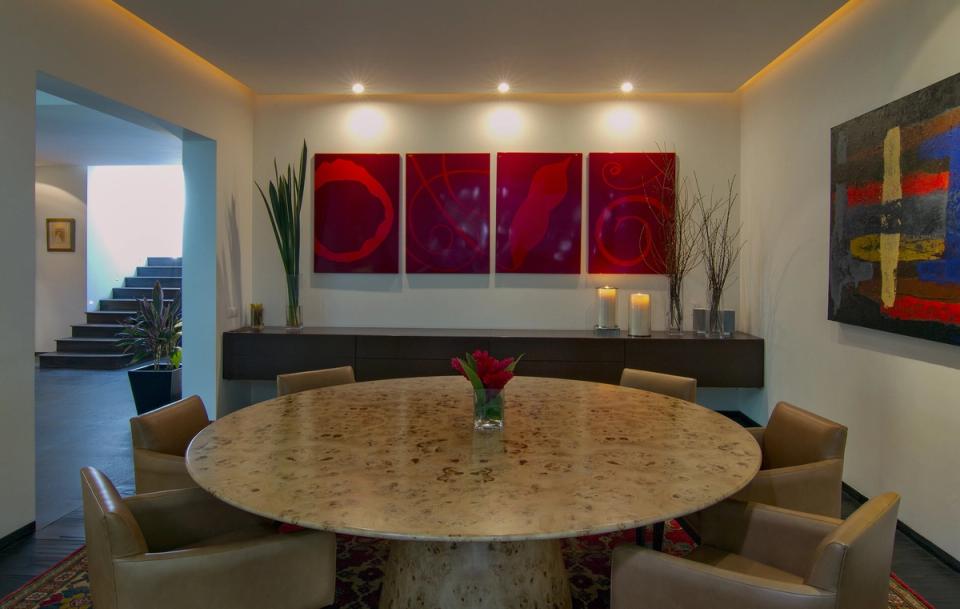 Comedor con mesa redonda y sillones tapizados bajo luz indirecta