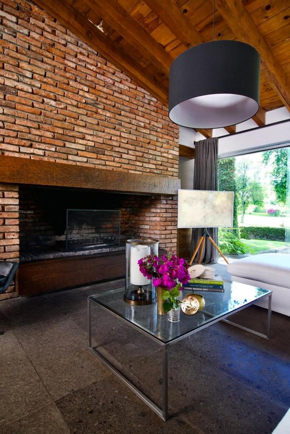 Chimenea de ladrillo aparente bajo techo de madera junto al ventanal