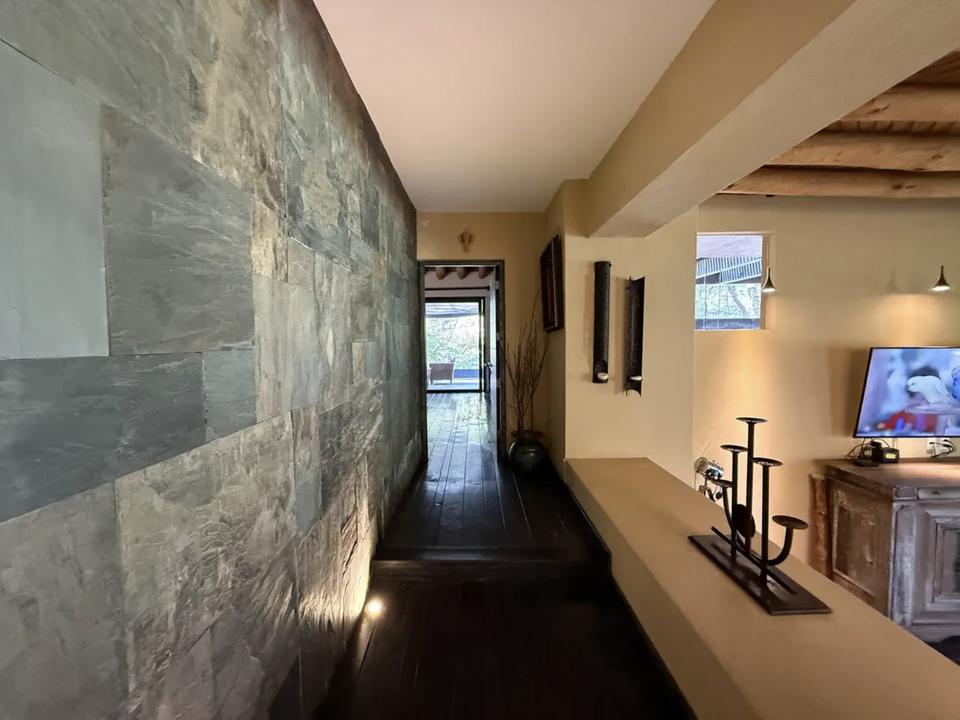 Pasillo junto a un muro de piedra iluminado desde el piso