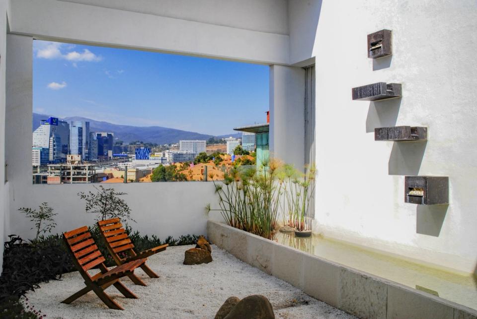 Terraza con jardín de grava y espejo de agua frente a la ciudad