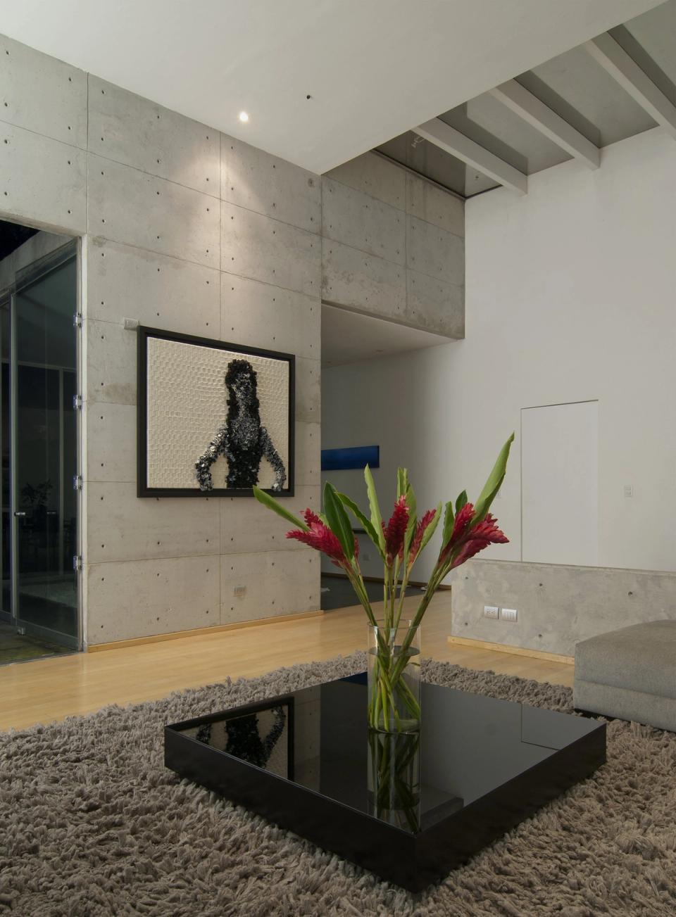 Estancia con muro de concreto, doble altura y piso de madera