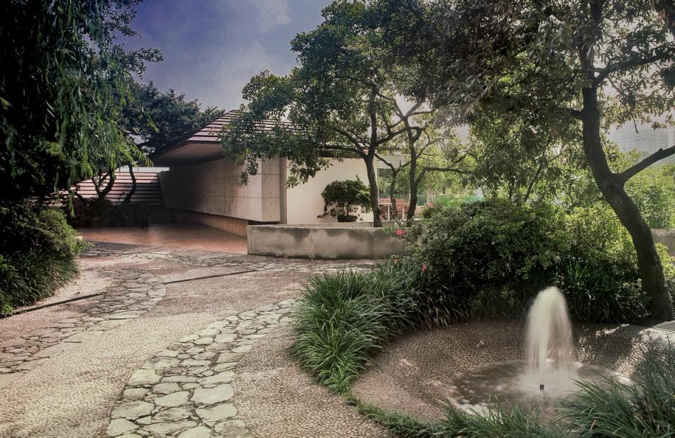 Jardín con fuente y camino de piedra frente a la casa